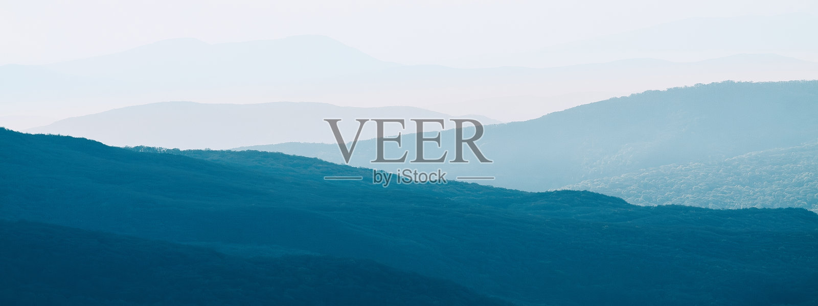 山脉的轮廓透过清晨的彩色雾气清晰可见。日落时分群山中宁静的晚景。壁纸照片。自然背景。全景。乌克兰克里米亚,照片摄影图片