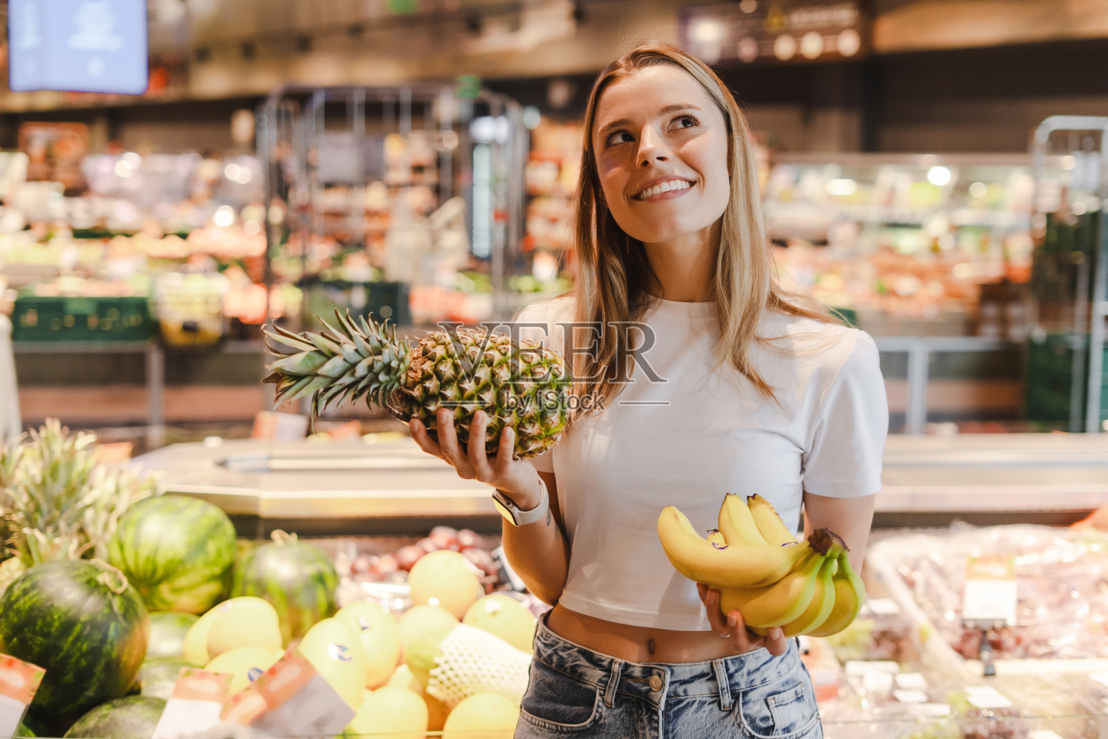 一名年轻女子在超市购物时选择菠萝和香蕉照片摄影图片