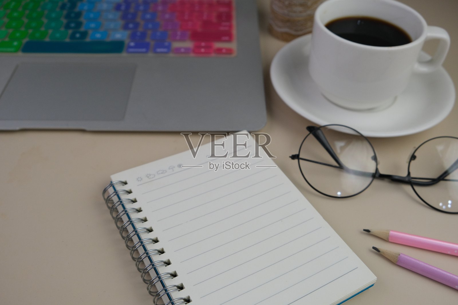 一张灰色的桌子上放着一杯咖啡、一台笔记本电脑和一本笔记本。教育、商务及办公理念。照片摄影图片