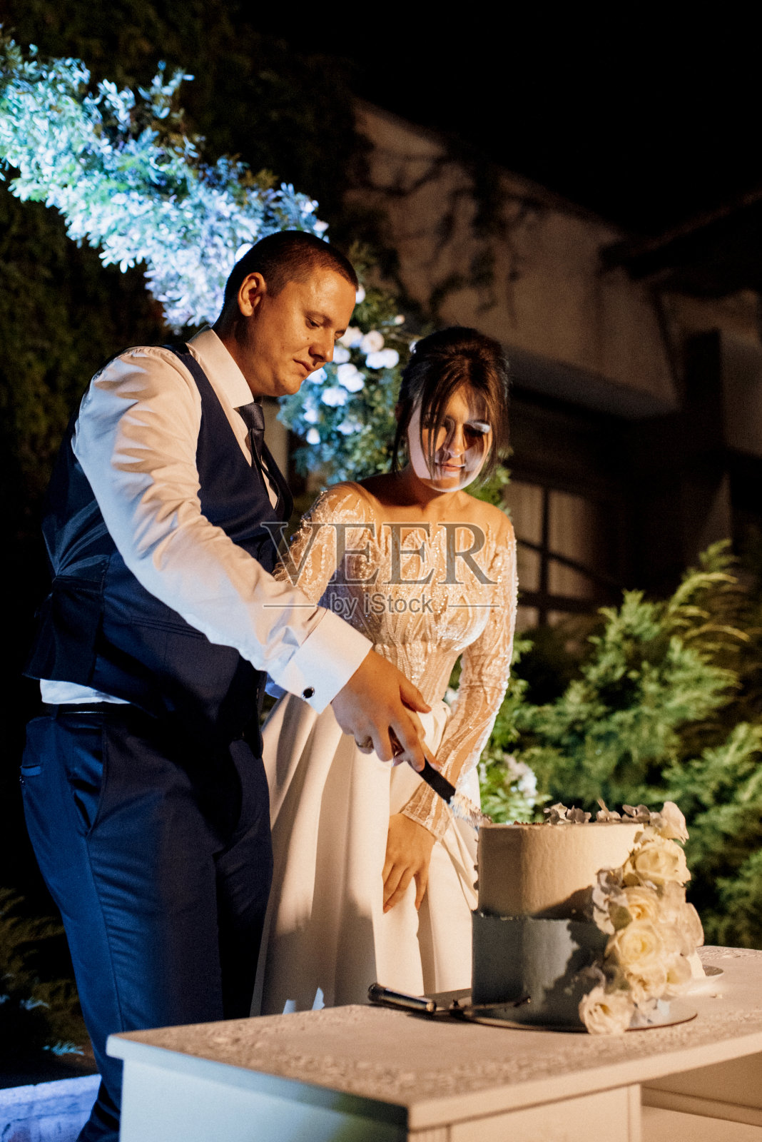 新婚夫妇高兴地切蛋糕，品尝婚礼蛋糕照片摄影图片