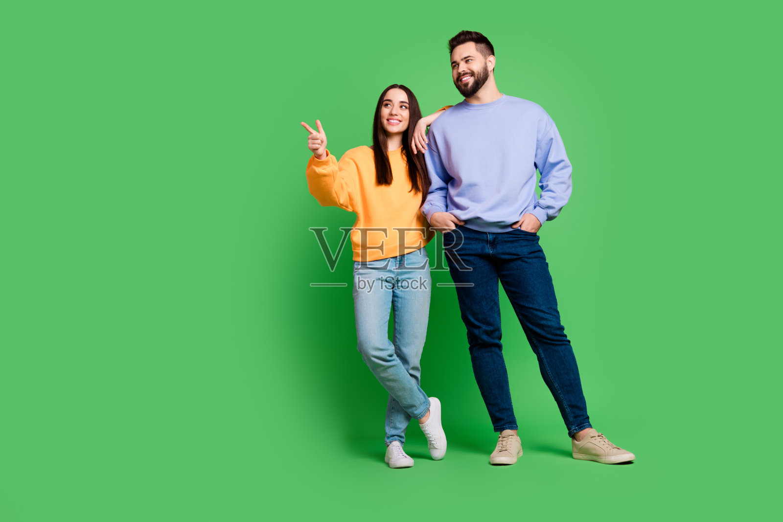 照片中迷人迷人的开朗夫妇穿着时髦的衣服，在绿色的背景下显得空空荡荡照片摄影图片