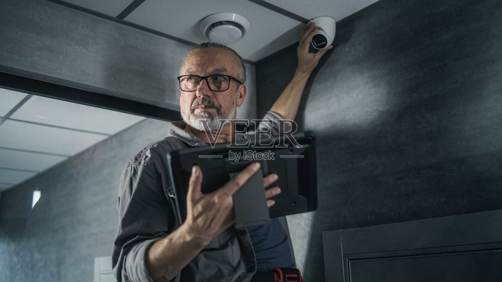 男技术人员使用平板电脑在办公室设置监控摄像头照片摄影图片