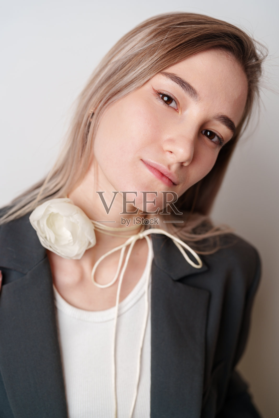 年轻女子戴着白色的花项链和灰色的运动夹克照片摄影图片