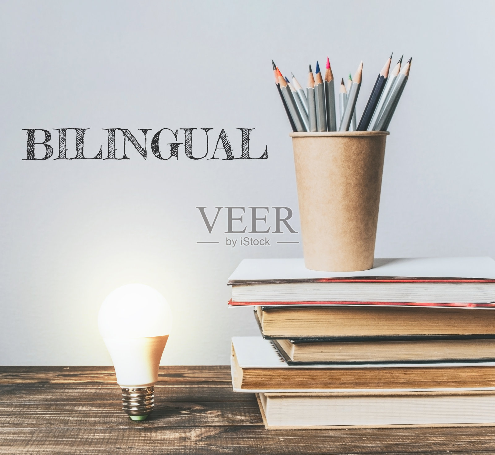 一摞书，上面放着一支铅笔和一个灯泡照片摄影图片