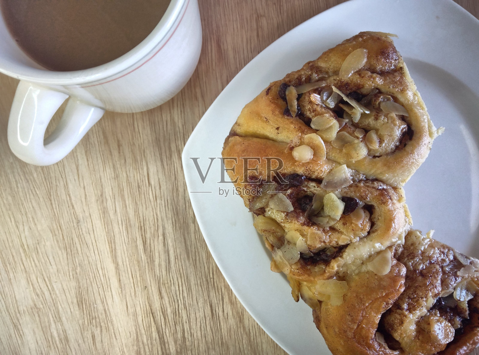 白色盘子上的苏里南Fiadoe的俯视图和一杯茶。木桌上的朗姆酒和葡萄干卷早餐。照片摄影图片