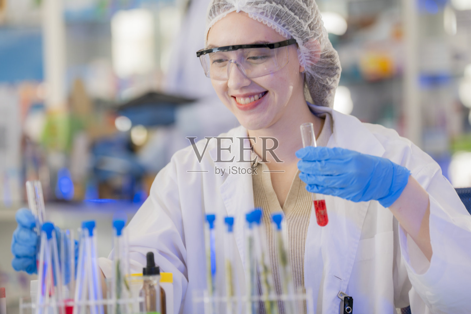 女科学家通过试管进行化学液体和植物样本的实验。在一个实验室里，在一个现代化的实验室里，通过安全、干净的测试，把测试样本放在后台。照片摄影图片