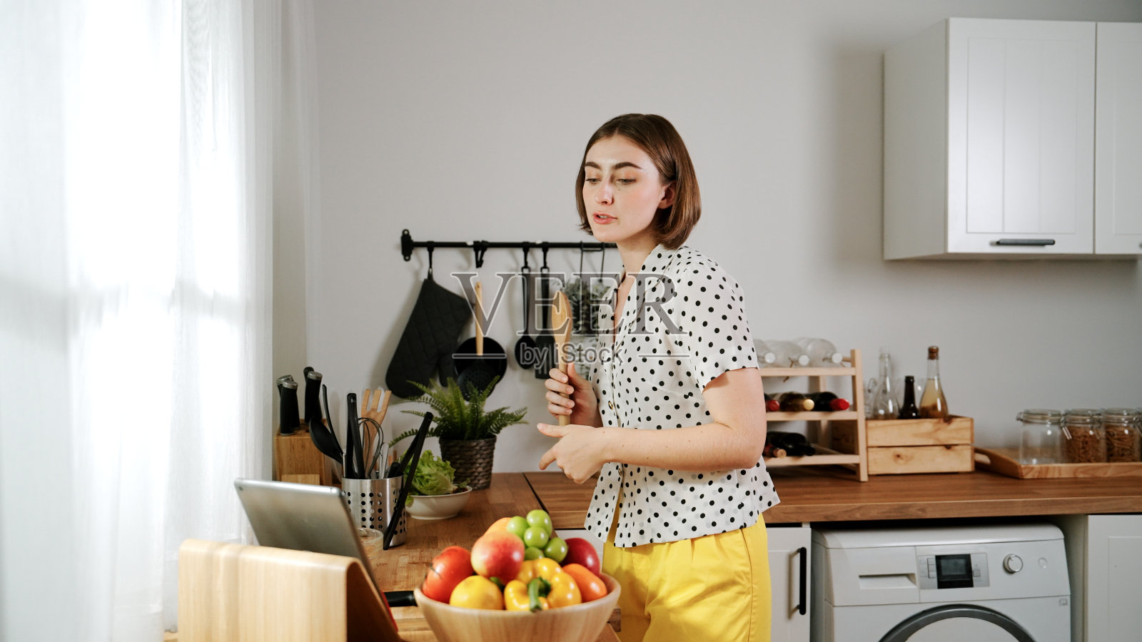 快乐的高加索母亲在现代厨房拿着勺子唱歌。教育学。照片摄影图片