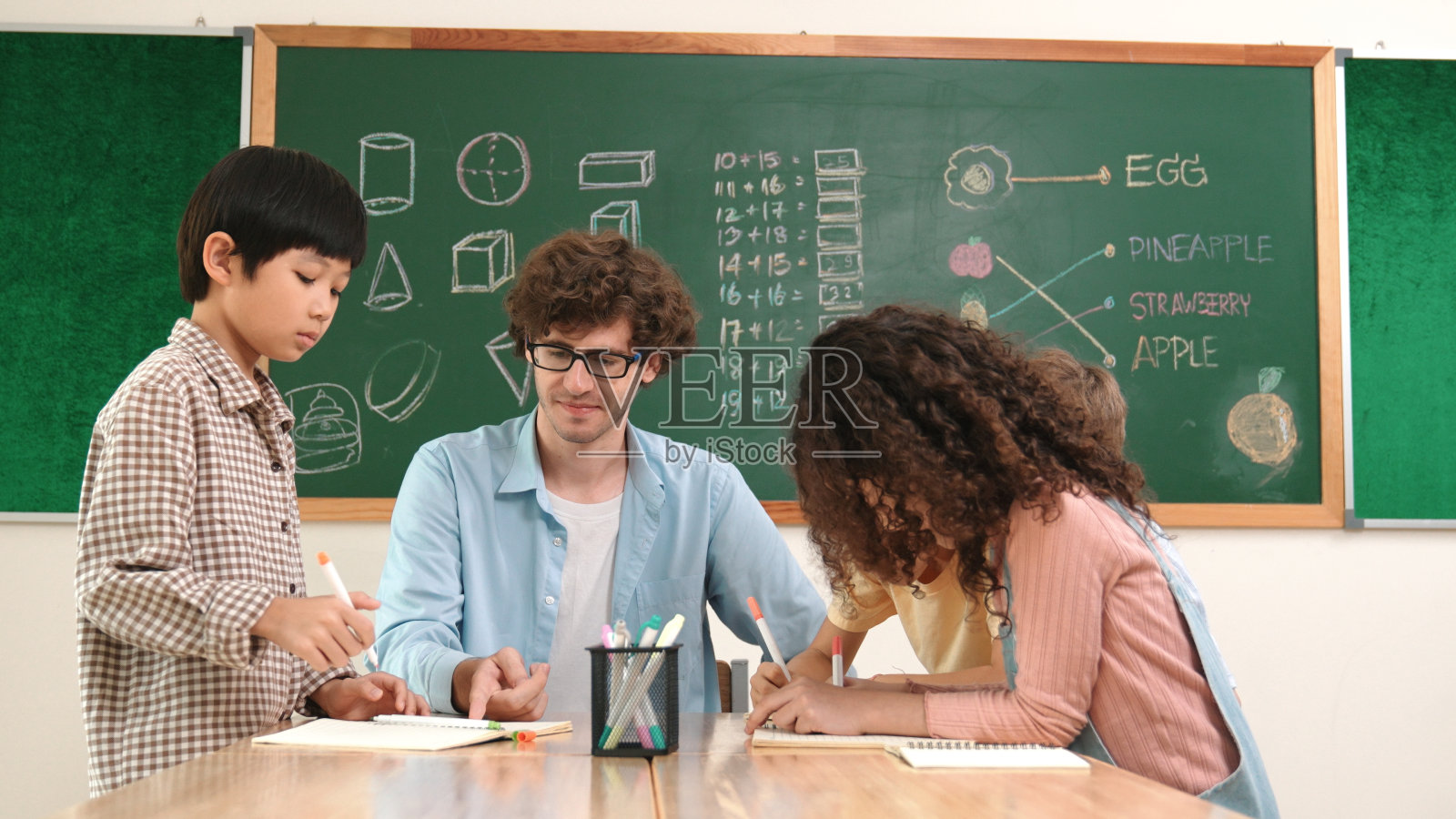 聪明的老师在不同的孩子画思维导图时解释想法。教育学。照片摄影图片