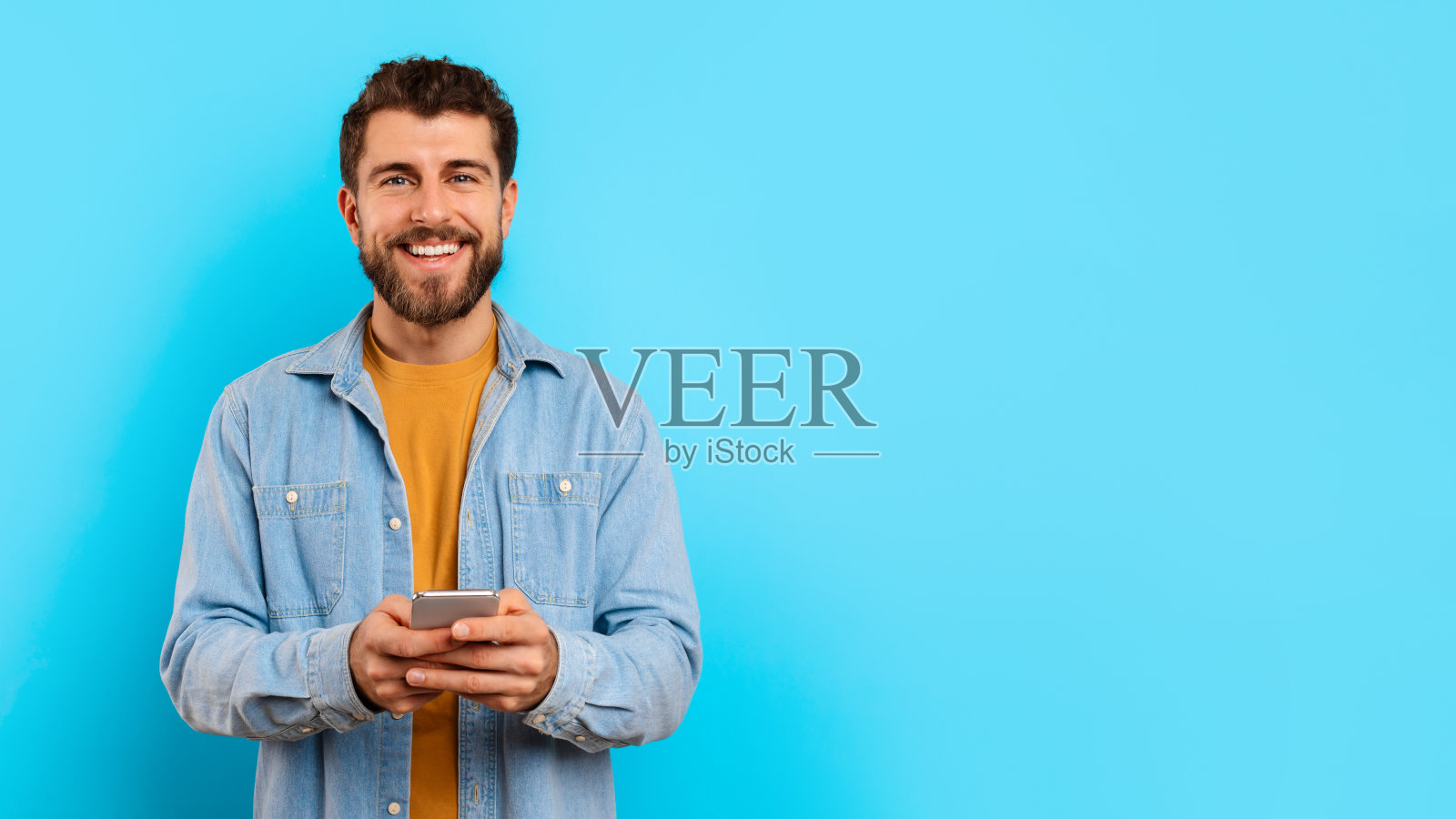 拿着智能手机，在蓝色的工作室背景下发短信照片摄影图片