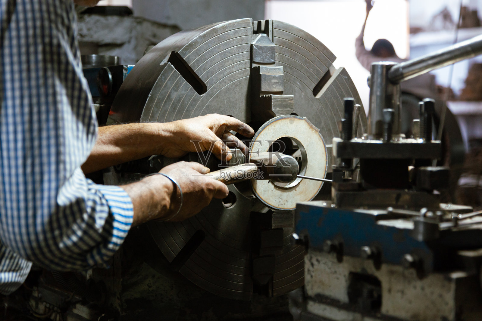 在原厂操作老式车床的老人。照片摄影图片