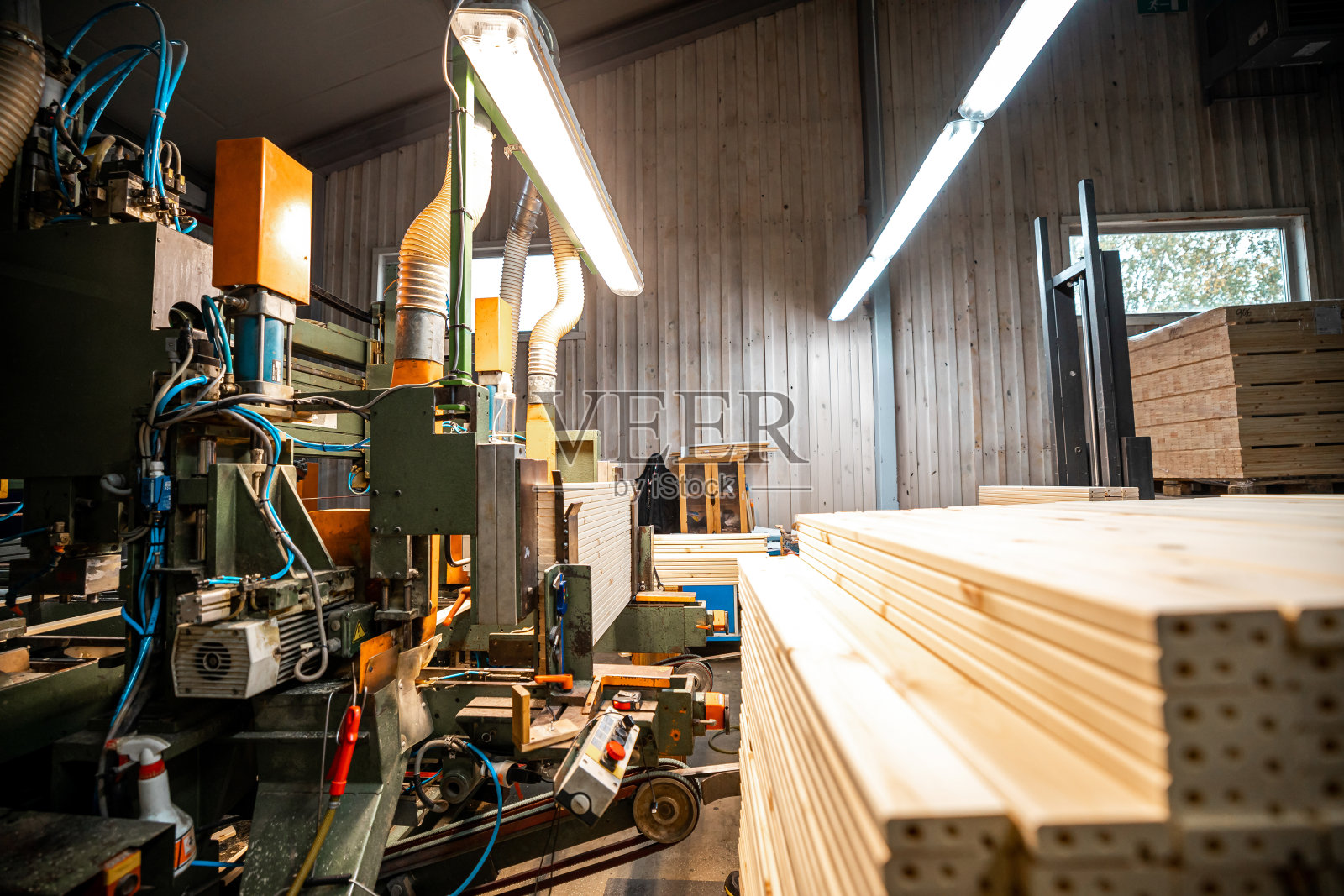 一个大型木工工厂，有成堆的新切割的木板准备加工，在光线充足的制造环境中展示工业效率和精度照片摄影图片