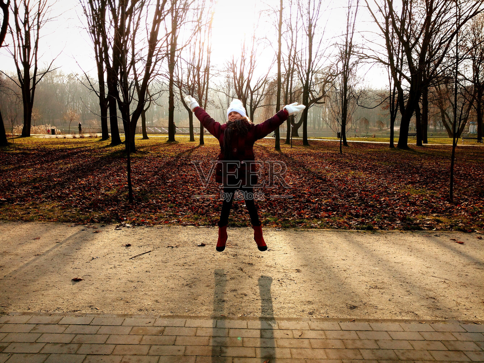 完整的快乐女孩在公园的人行道上跳跃照片摄影图片