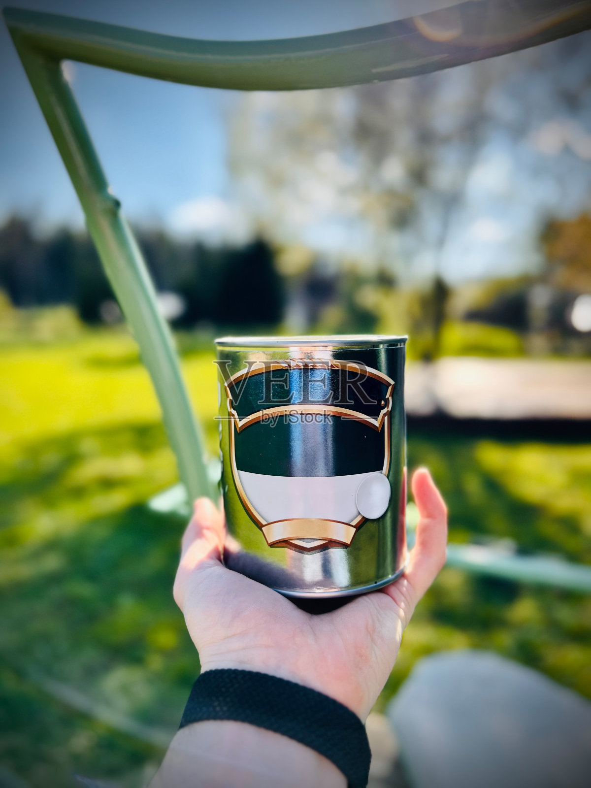 在一个阳光明媚的日子里，手拿着一罐金属漆在户外照片摄影图片