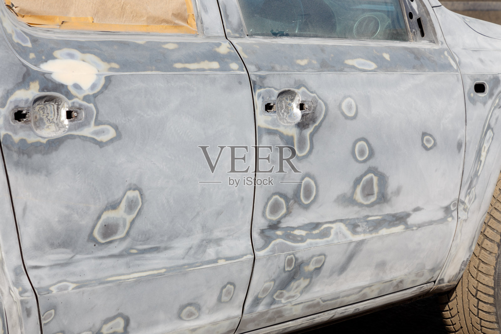 事故后的车体先涂上油灰，再涂底漆。将汽车拆开，在喷漆室进行喷漆准备。给汽车上漆的过程。照片摄影图片