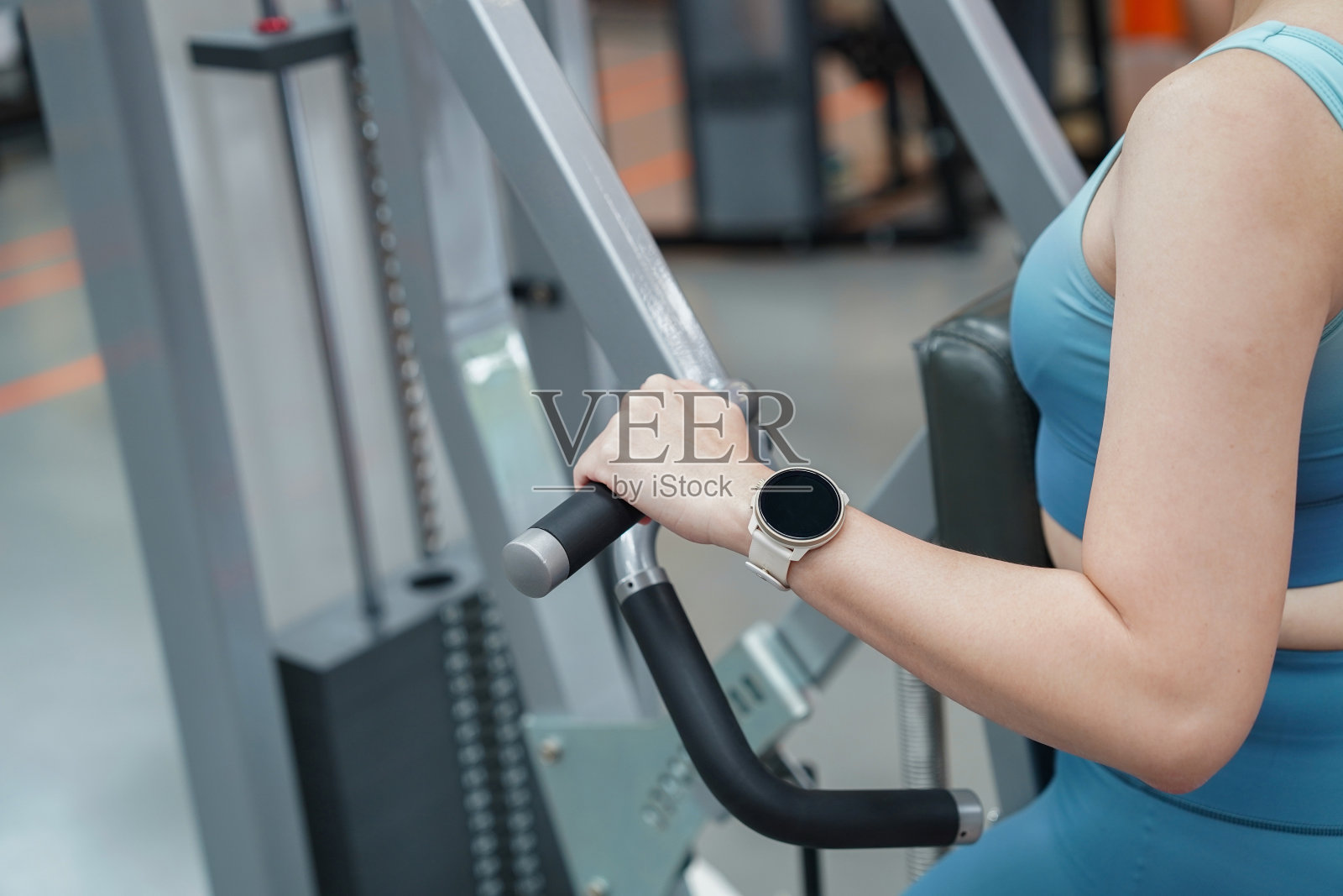 女性手持智能手表在健身房锻炼的特写。照片摄影图片
