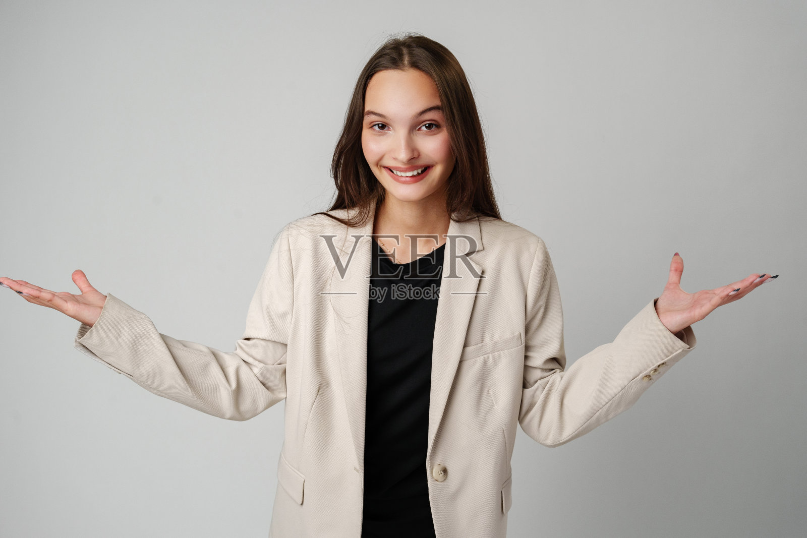 身穿米色运动夹克的年轻女子张开手掌做手势照片摄影图片