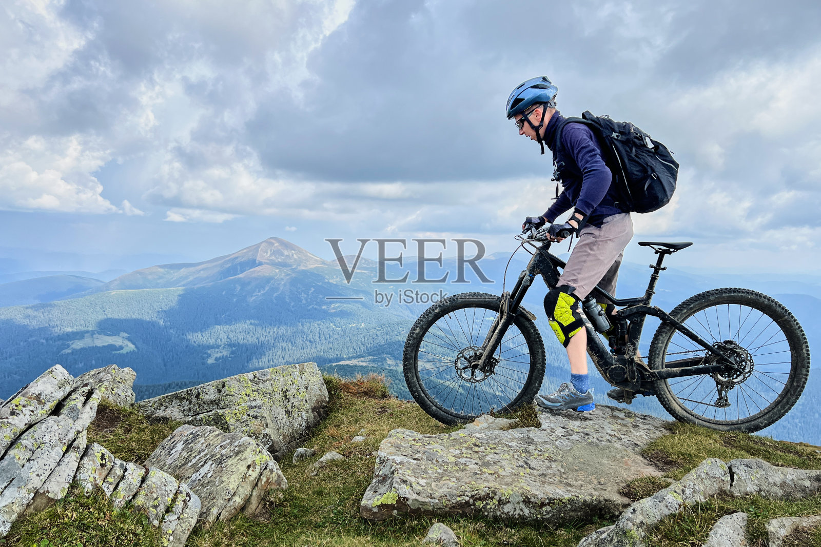 骑电动山地车的人沿着山上长满草的小路在户外骑行。照片摄影图片
