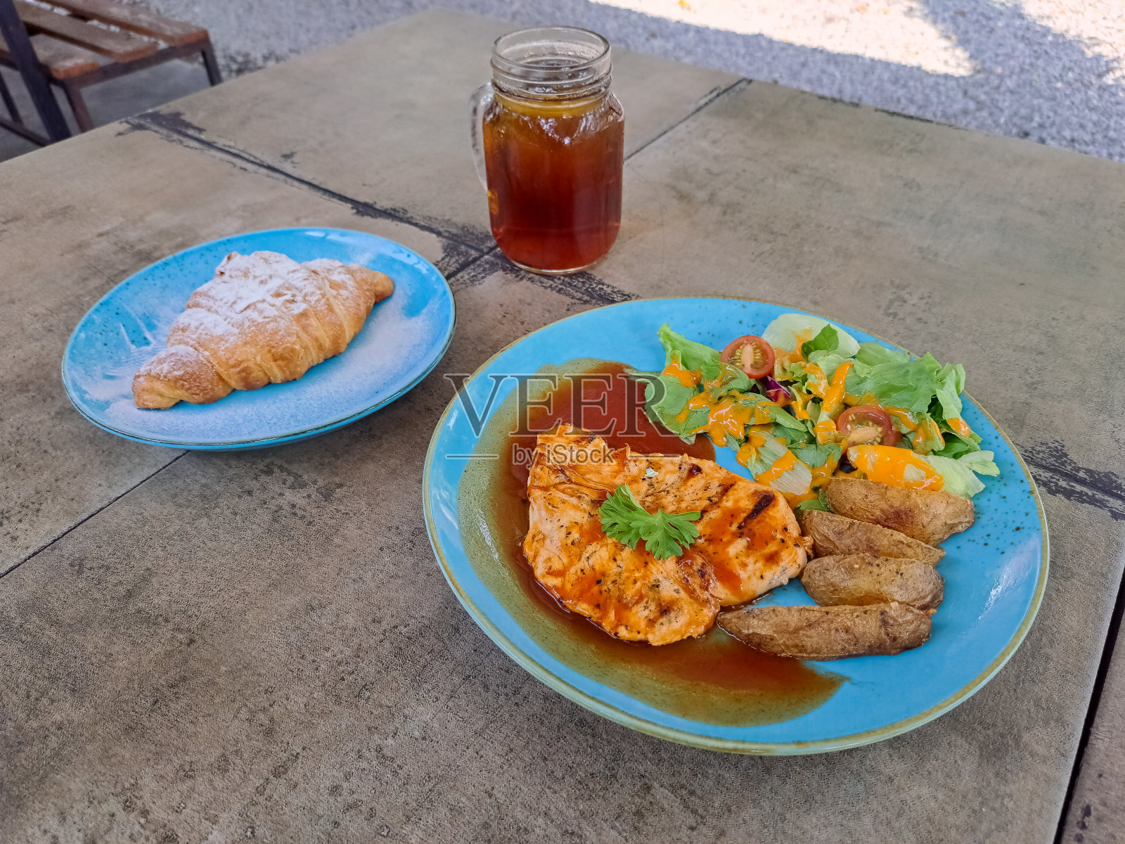 美味的烤鸡烧烤酱配鸡块，土豆角和混合蔬菜。盘子里的新鲜脆皮羊角面包。新鲜的茶冰在玻璃杯里。食物和饮料菜单。照片摄影图片