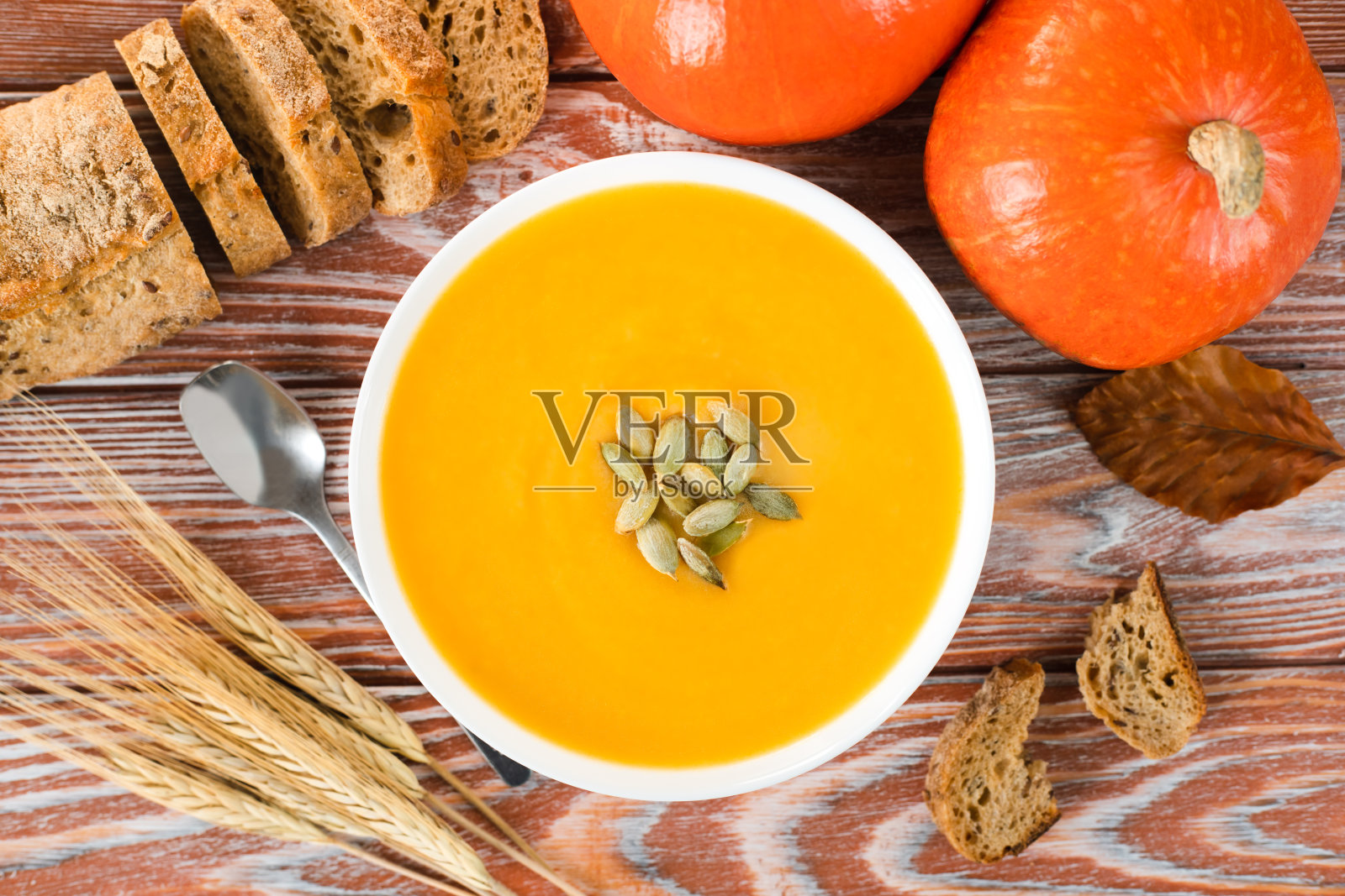 南瓜奶油汤配黑麦面包和木制背景上的南瓜。时令蔬菜菜单。前视图。特写镜头。照片摄影图片