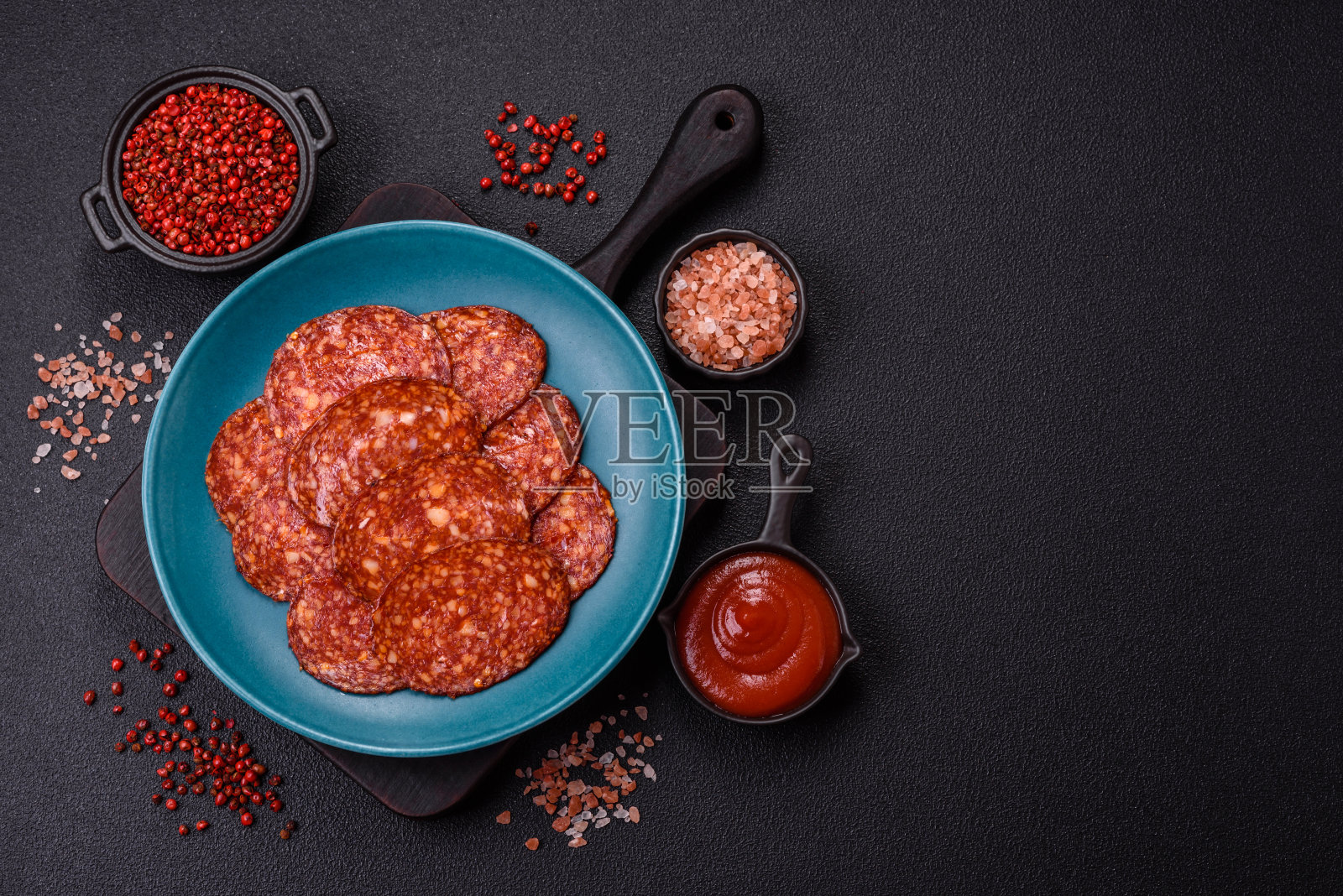 美味的烟熏意大利辣香肠切片，配以盐、香料和香草照片摄影图片