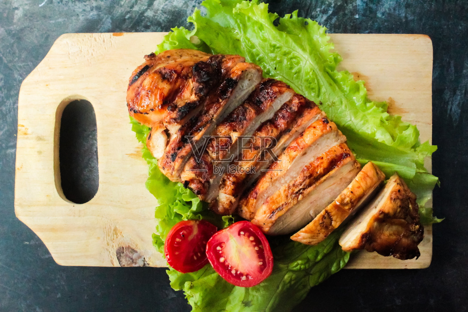 切成薄片的烤鸡胸肉和蔬菜放在砧板上照片摄影图片