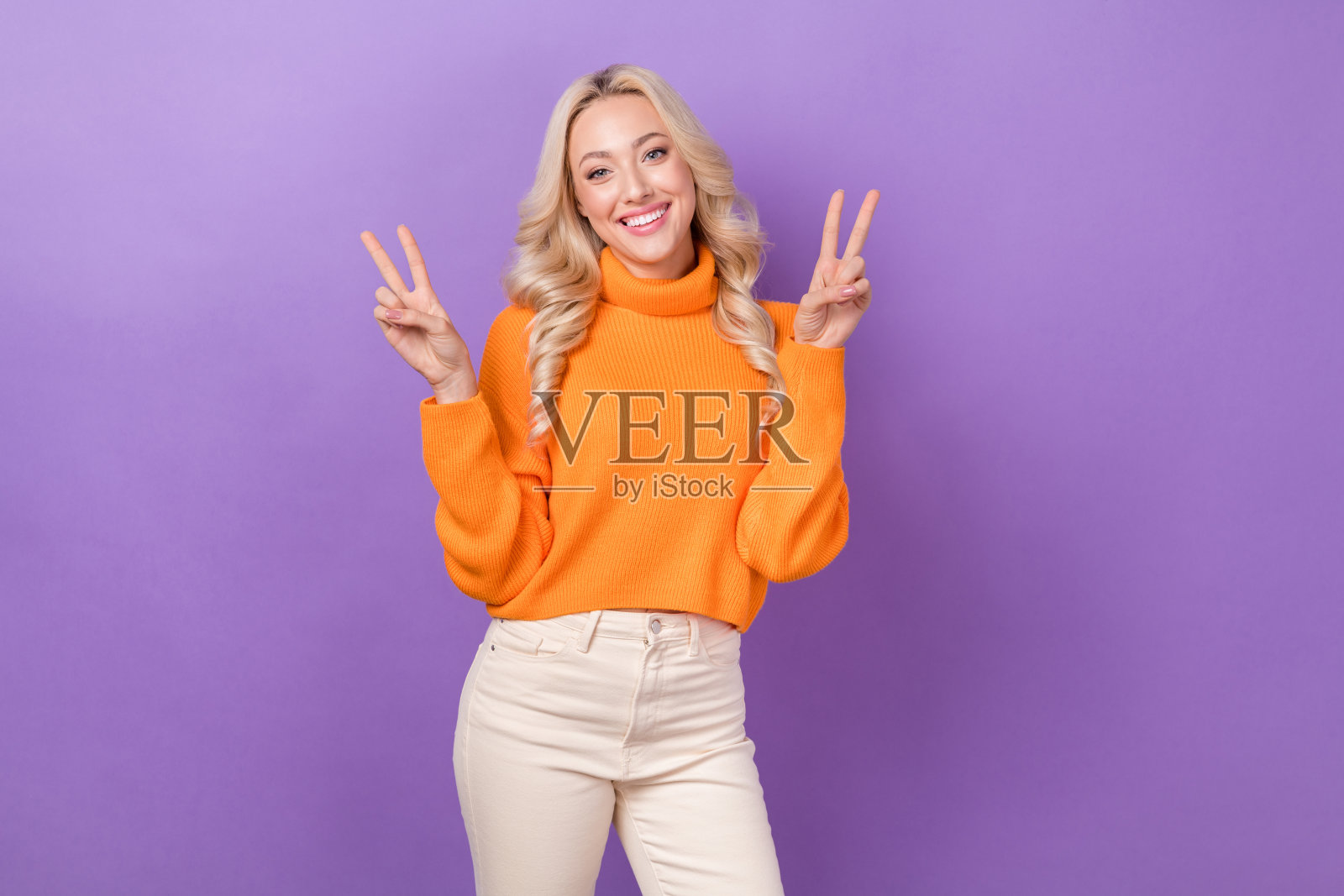 肖像少女可爱的女人优雅的发型，穿套头衫，双手显示v字形符号孤立在紫罗兰色背景照片摄影图片