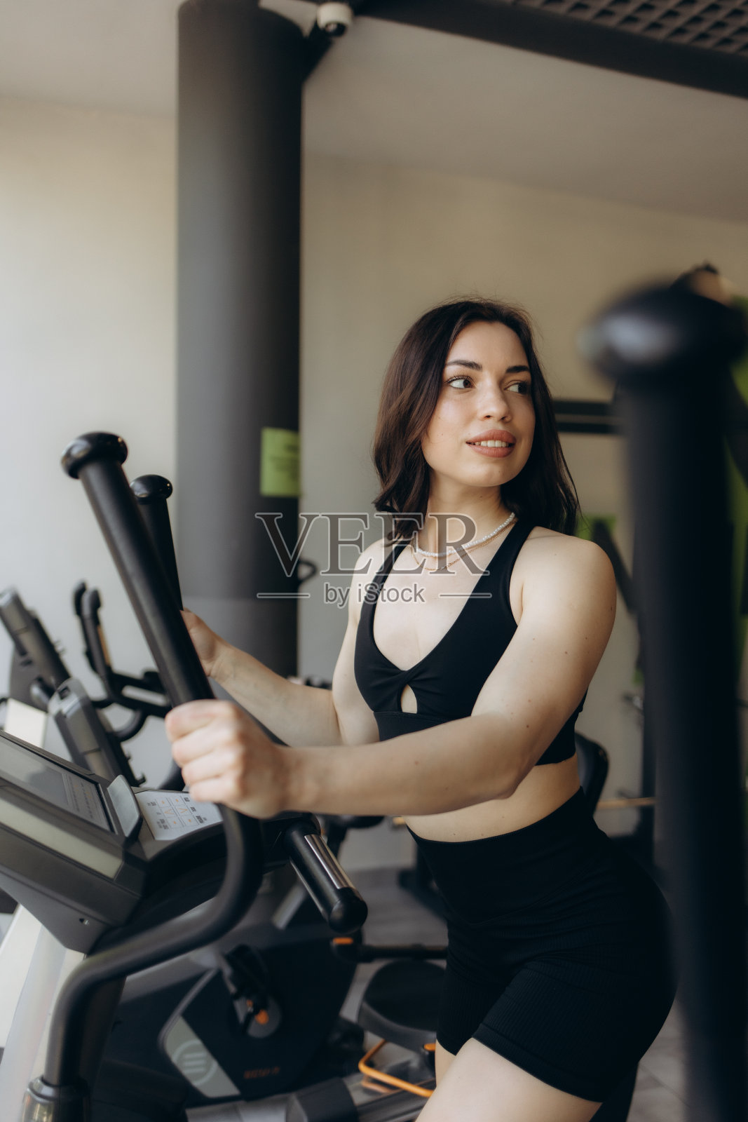 迷人的年轻女子正在健身房的椭圆机上锻炼照片摄影图片