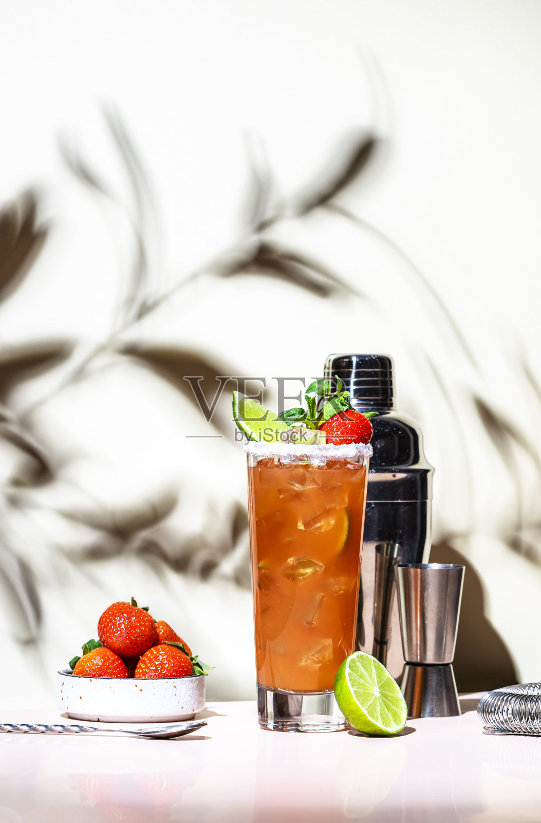 草莓酒精鸡尾酒，由龙舌兰酒、柚子、酸橙汁、薄荷和冰块混合而成。米色粉色背景。，强光照片摄影图片