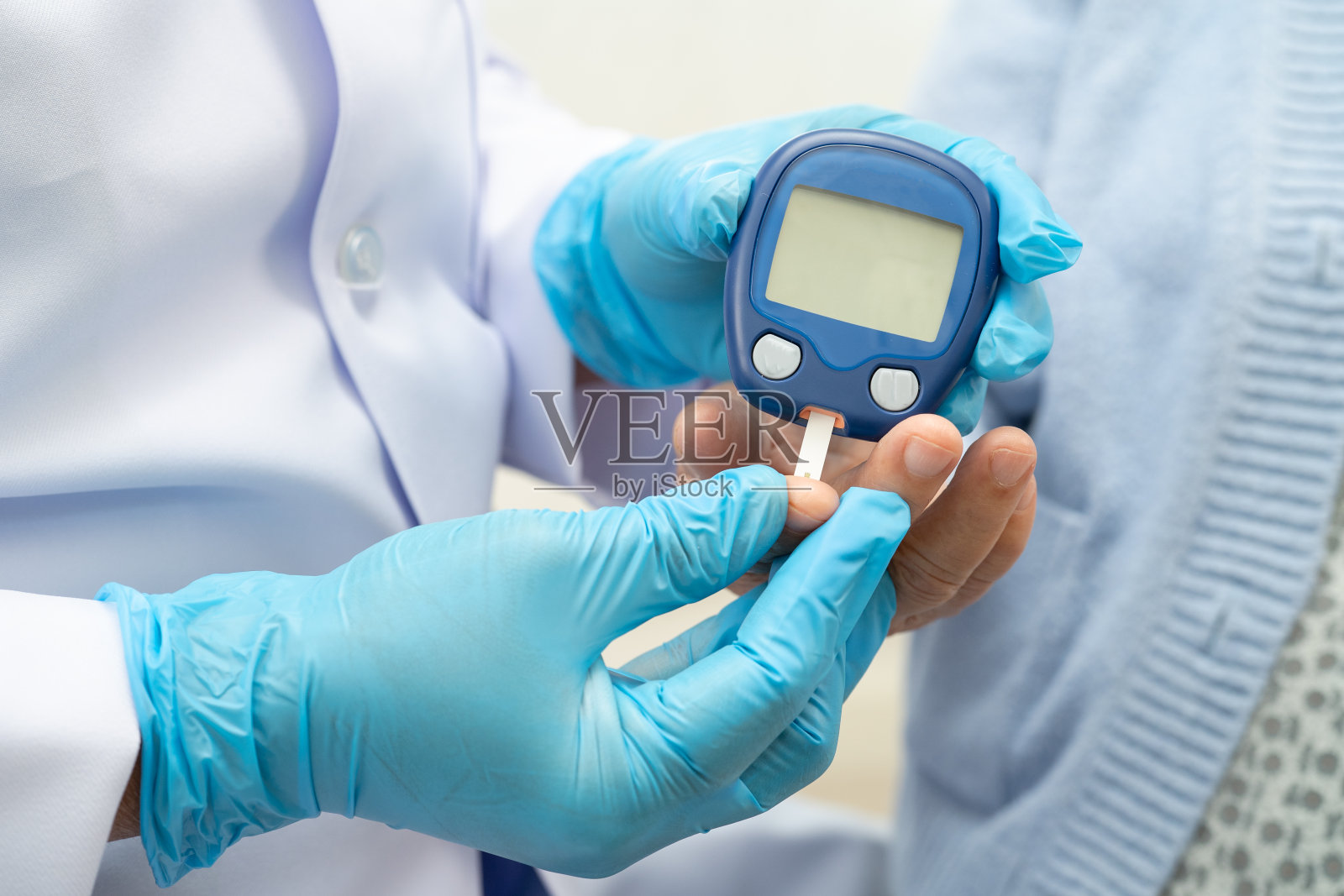 医生使用数字血糖监测仪测量和测试条从手指血糖水平检查糖尿病。照片摄影图片