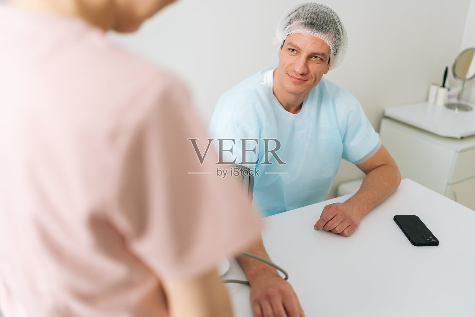 医学门诊检查中男性患者测血压的肩拍。女护士正在检查病人的动脉血压。照片摄影图片