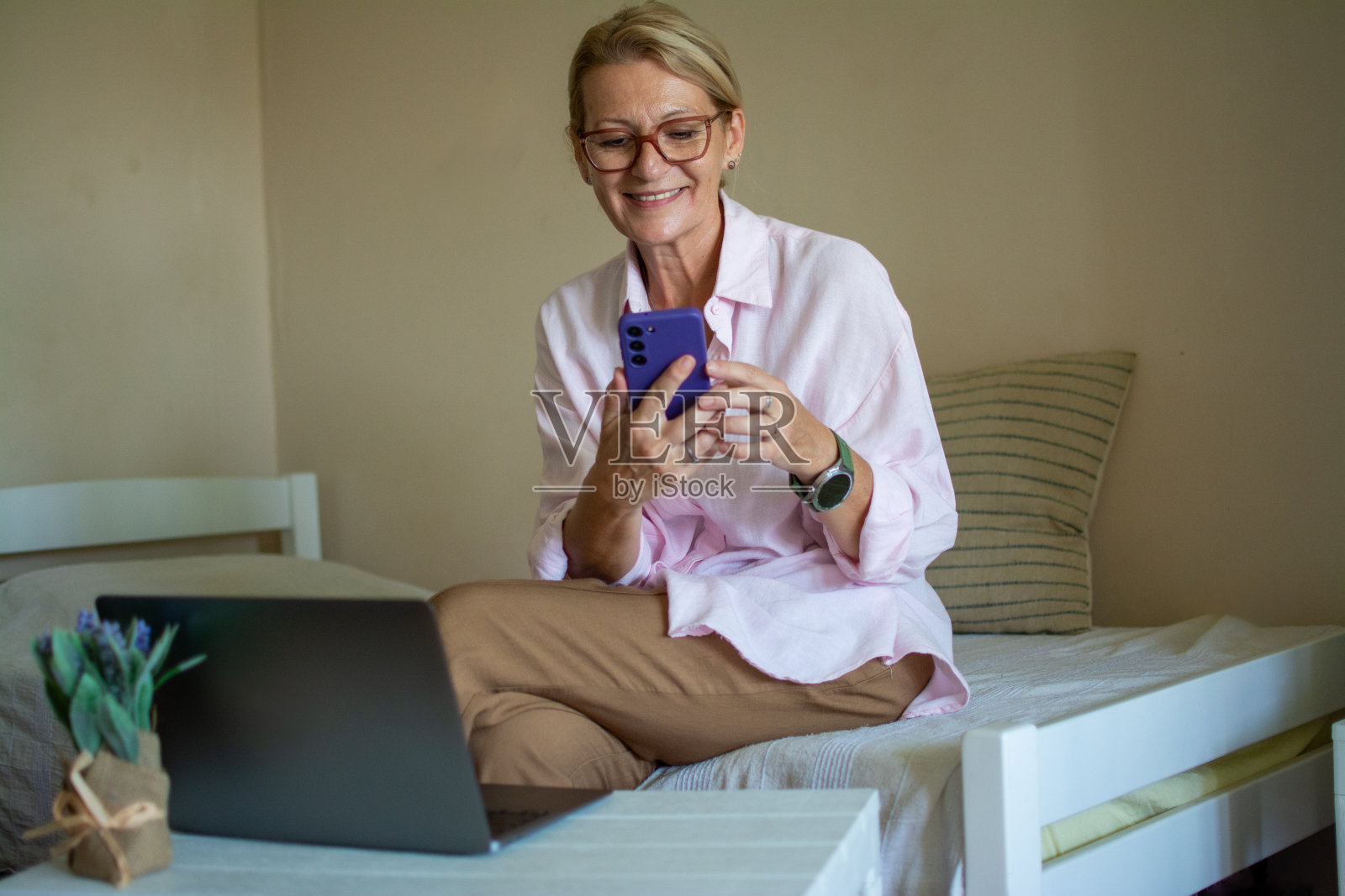 成熟的金发女人坐在沙发上用笔记本电脑进行视频咨询照片摄影图片