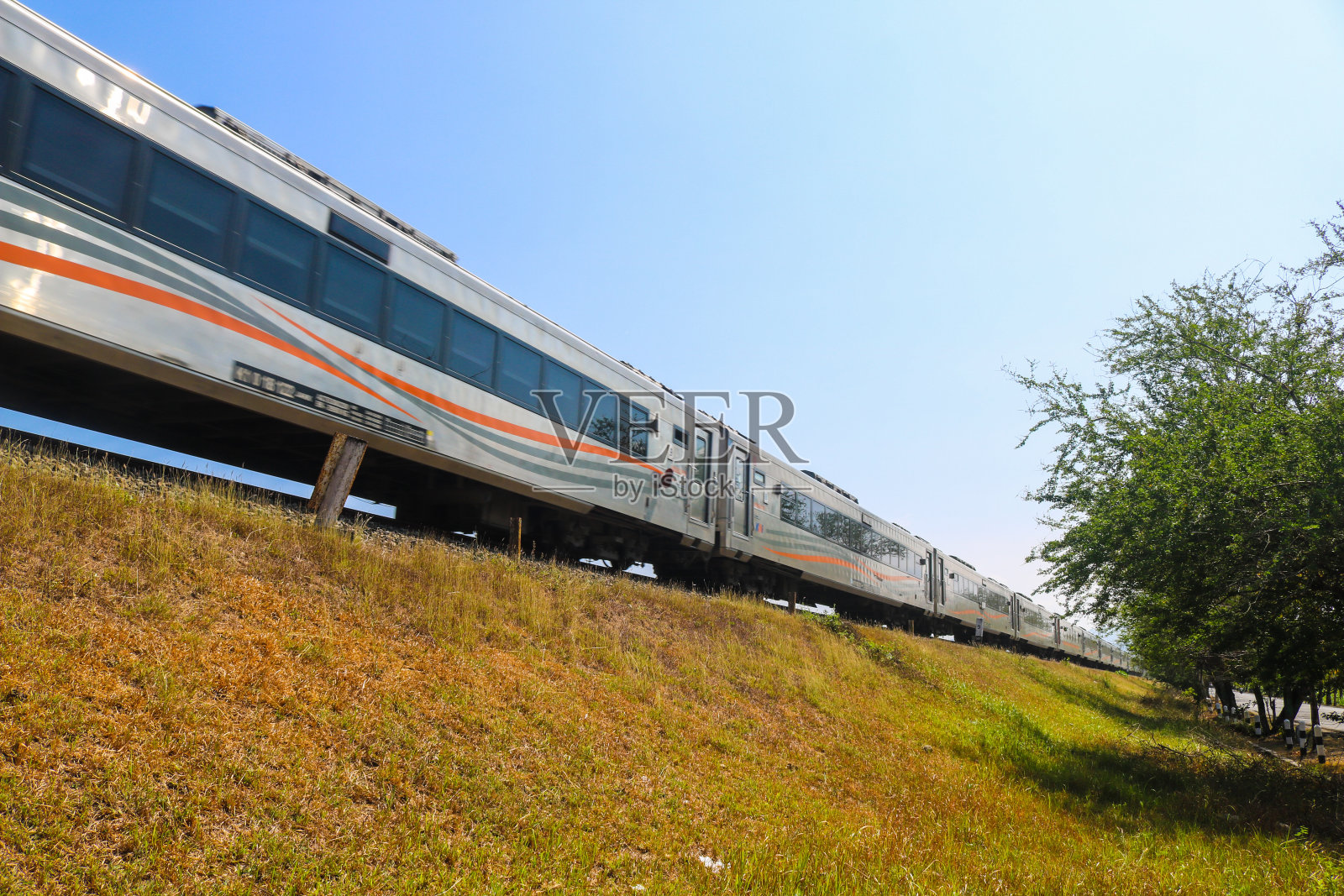 印尼火车在轨道上穿过乡村，可以看到草原和蓝天。印尼Kereta Api (KAI)照片摄影图片