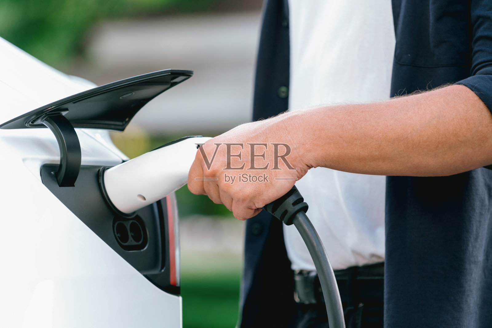 一名男子在旅途中给电动汽车充电。高举照片摄影图片