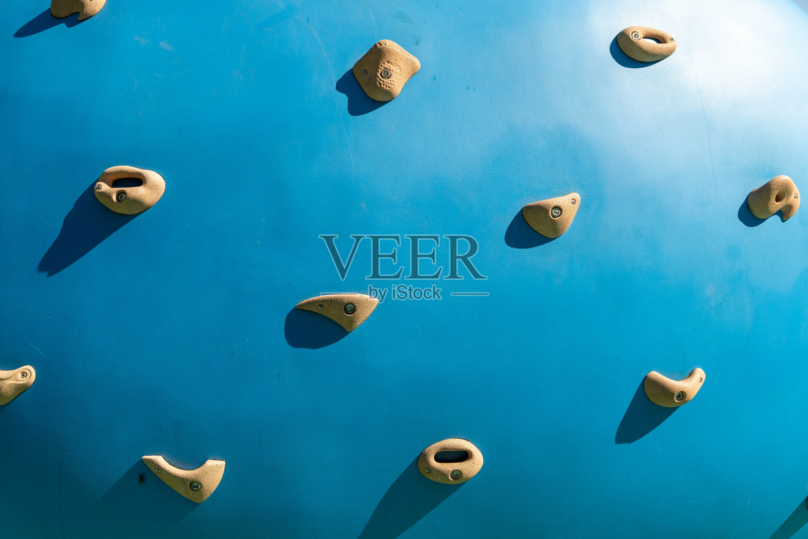 一个带有米色把手的蓝色攀岩墙的特写照片摄影图片