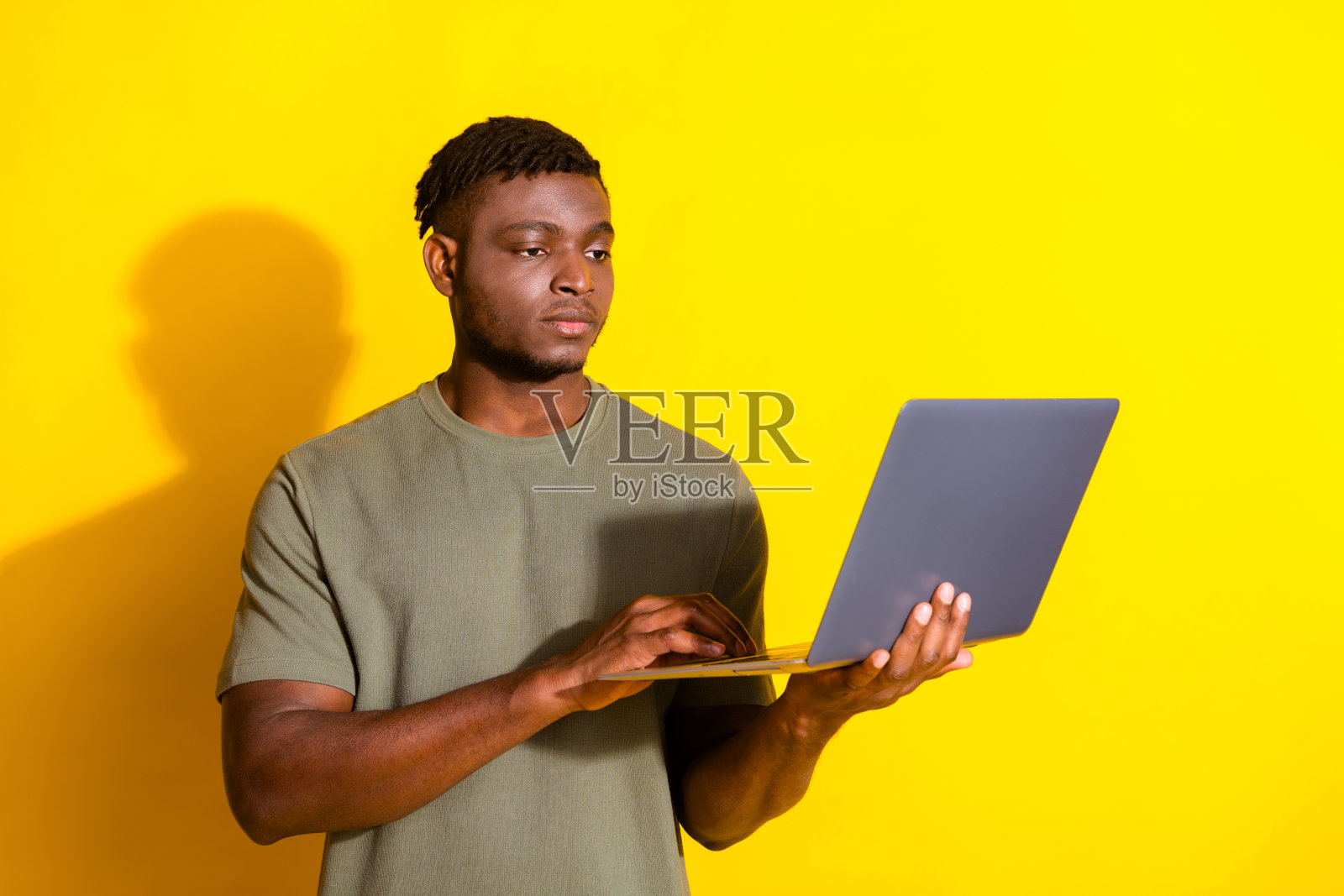 照片中英俊迷人的男人穿着时髦的卡其色衣服，在黄色背景上打字发短信照片摄影图片