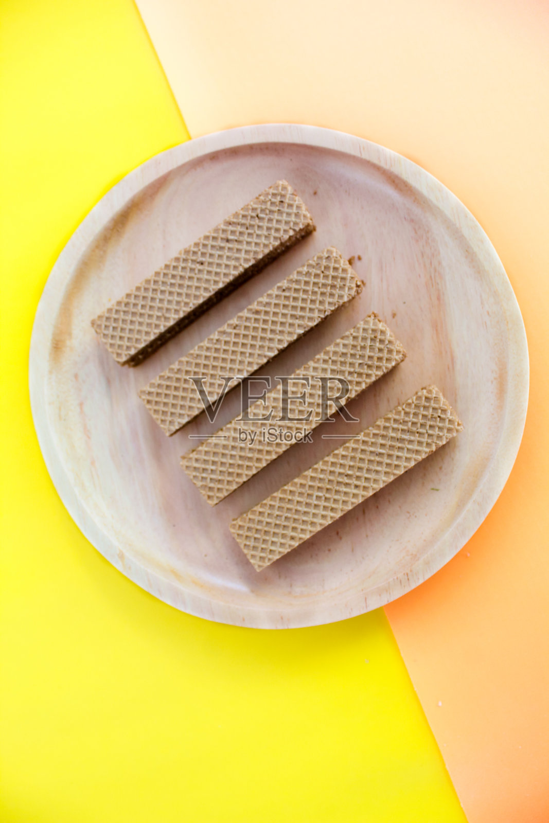木制盘子上的巧克力华夫饼被隔离在橙色和黄色的背景上。脆脆的点心甜点。美食摄影概念照片摄影图片