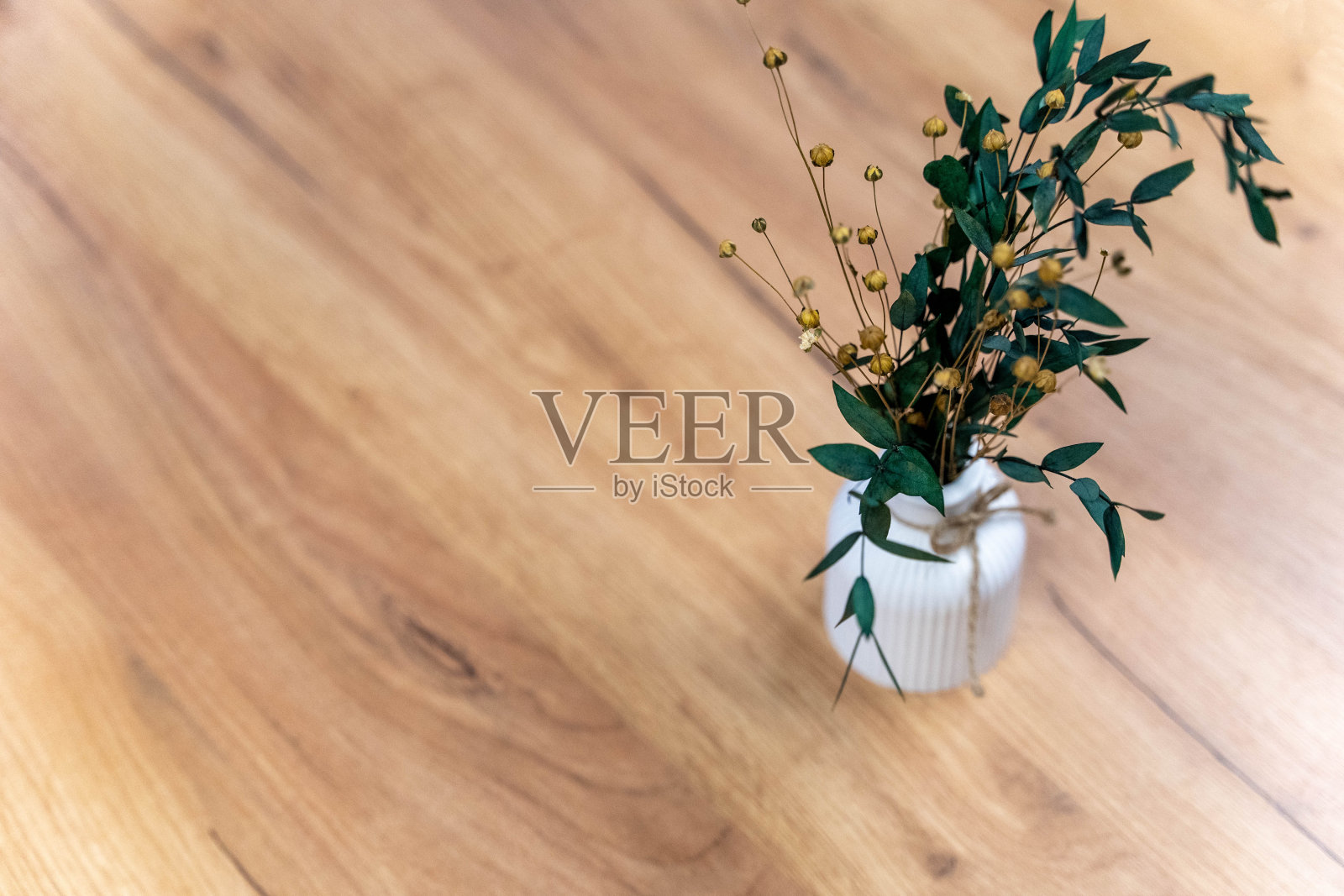 在木制表面的小花瓶里装上干叶子和花照片摄影图片