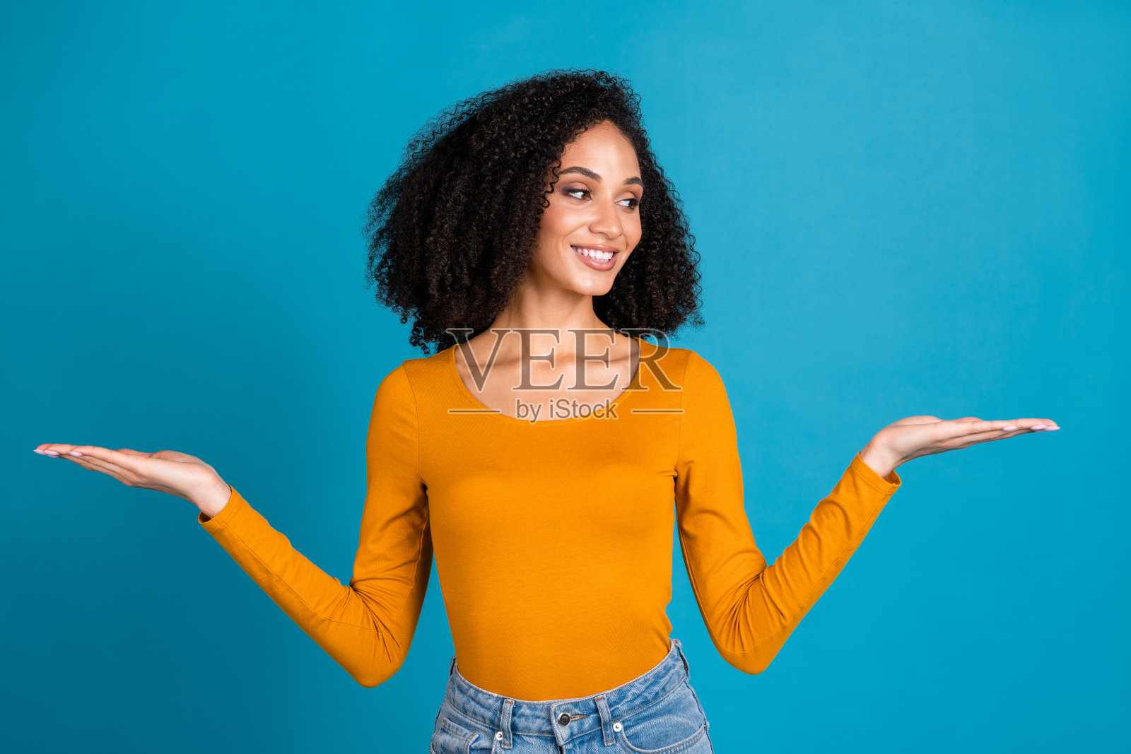 照片中迷人的年轻女子的肖像比较空看，穿着时髦的橙色衣服孤立在蓝色的背景照片摄影图片