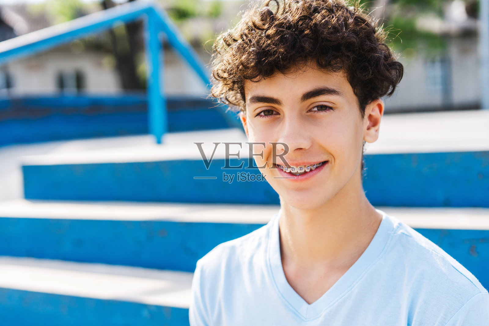 一个十几岁的男孩，穿着休闲的衣服，戴着牙套，微笑着看着镜头照片摄影图片