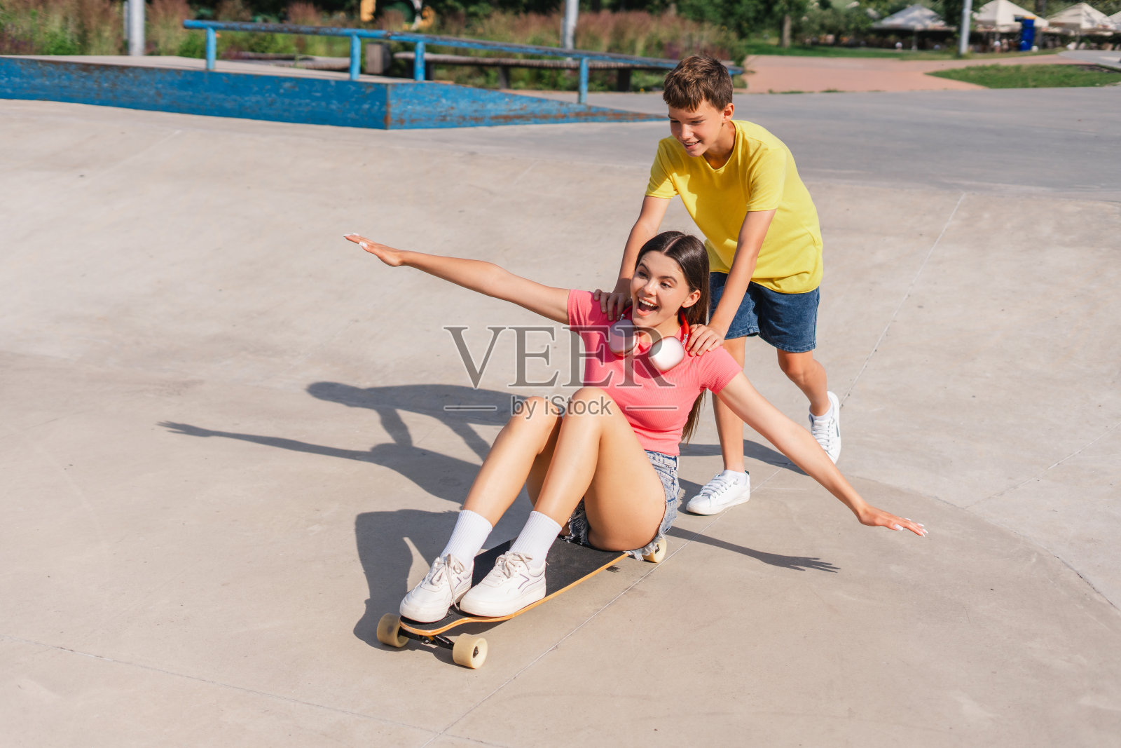 兴奋、微笑的青少年朋友们在城市街道上玩滑板照片摄影图片