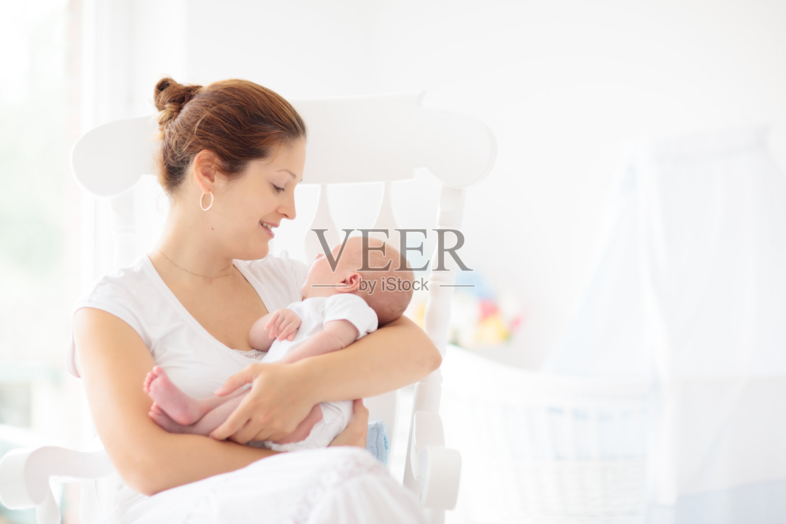 年轻的母亲抱着刚出生的婴儿。照片摄影图片