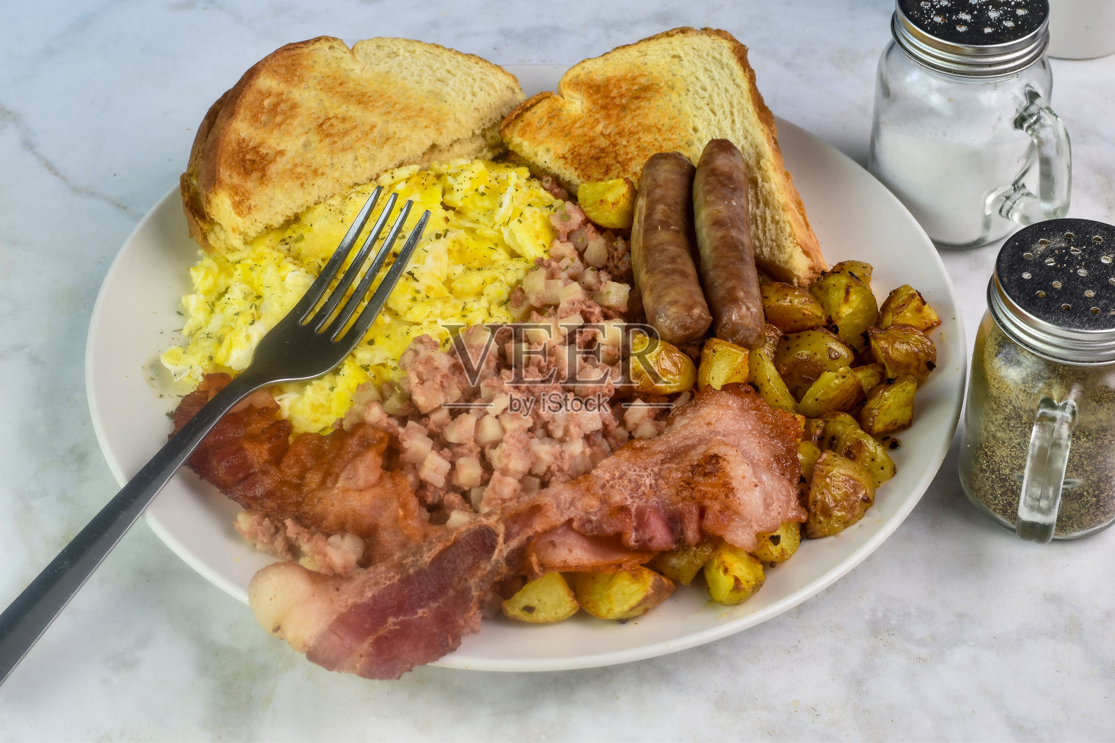 炒鸡蛋配家庭薯条，培根香肠和吐司照片摄影图片