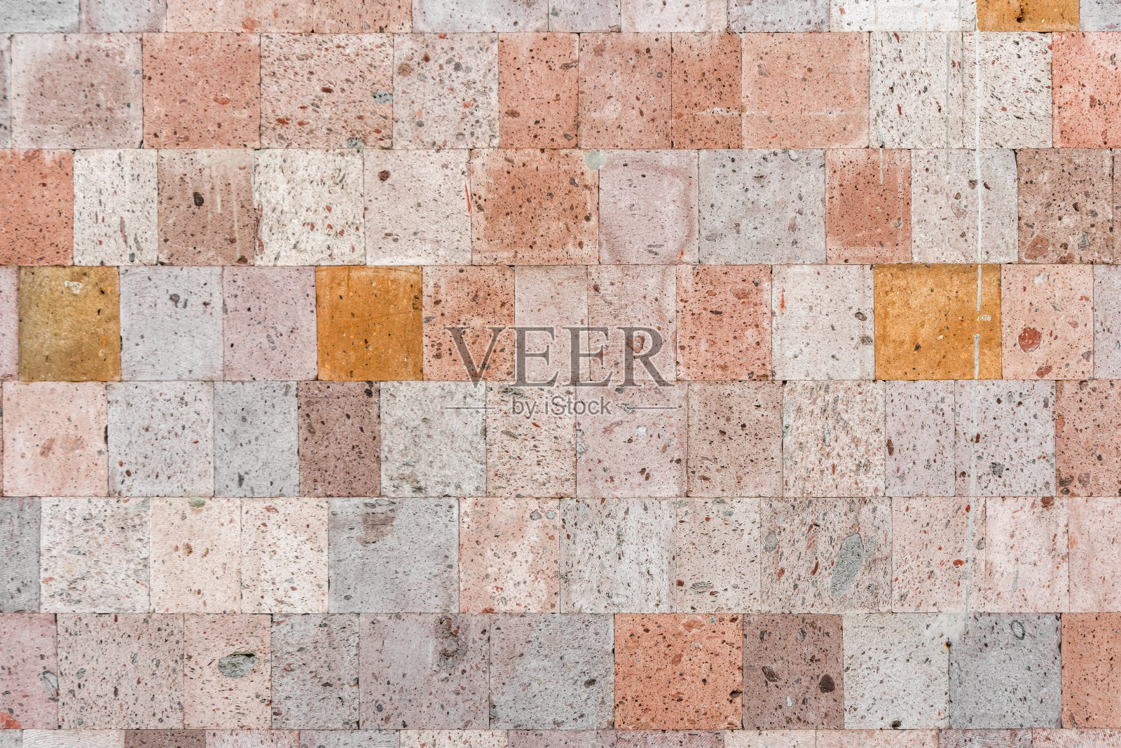 有纹理的墙壁内衬着各种色调的火山凝灰岩瓷砖。照片摄影图片