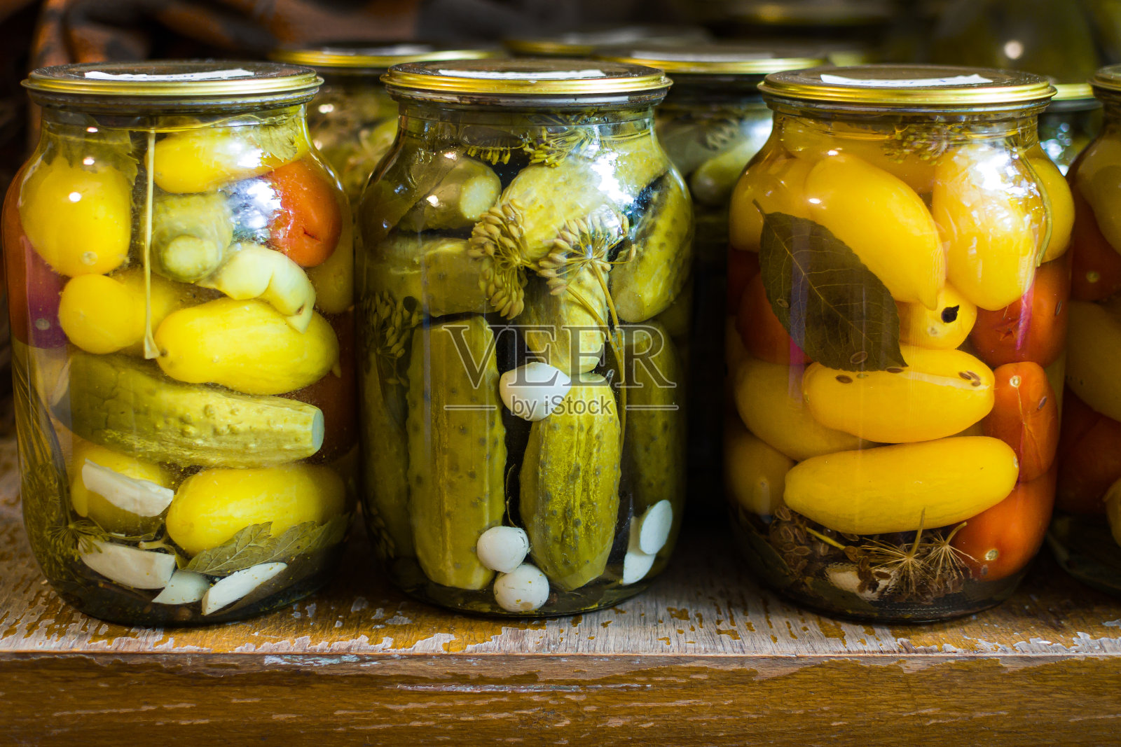 玻璃罐里的罐装蔬菜。小屋桌上的发酵蔬菜。秋天的收获。自制烹饪准备。酸洗番茄、黄瓜、大蒜、生菜、胡萝卜。照片摄影图片