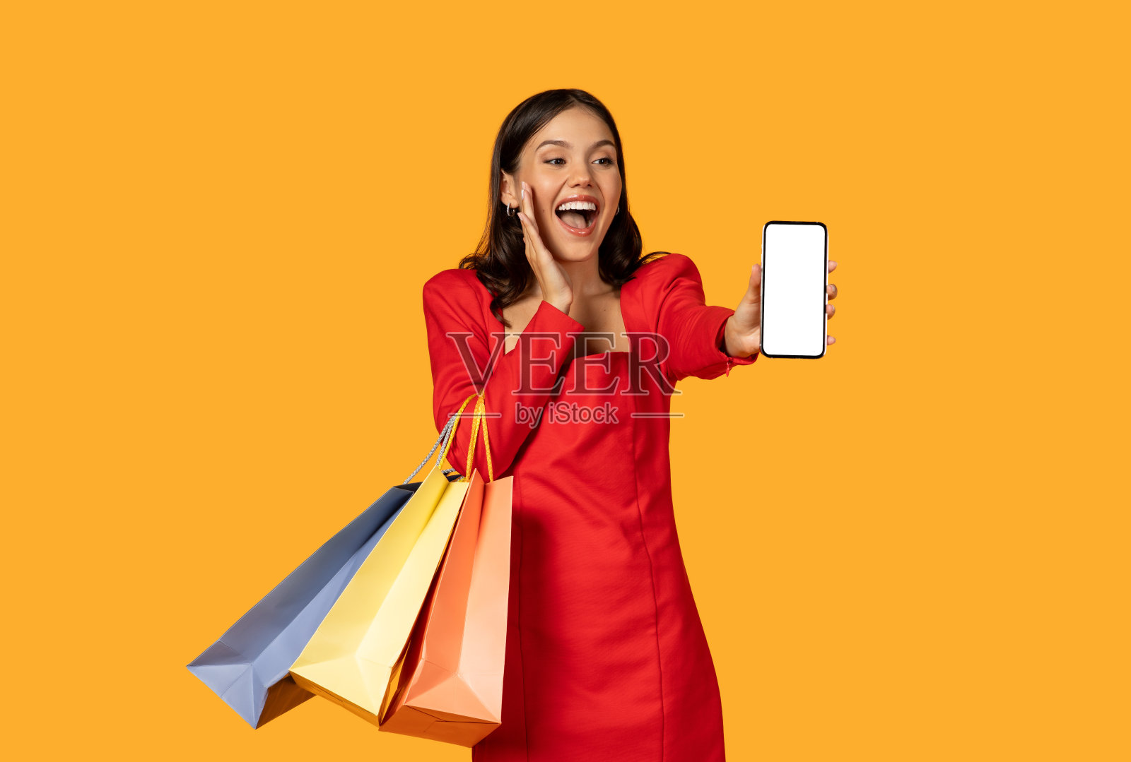 兴奋的红裙年轻女子展示智能手机照片摄影图片