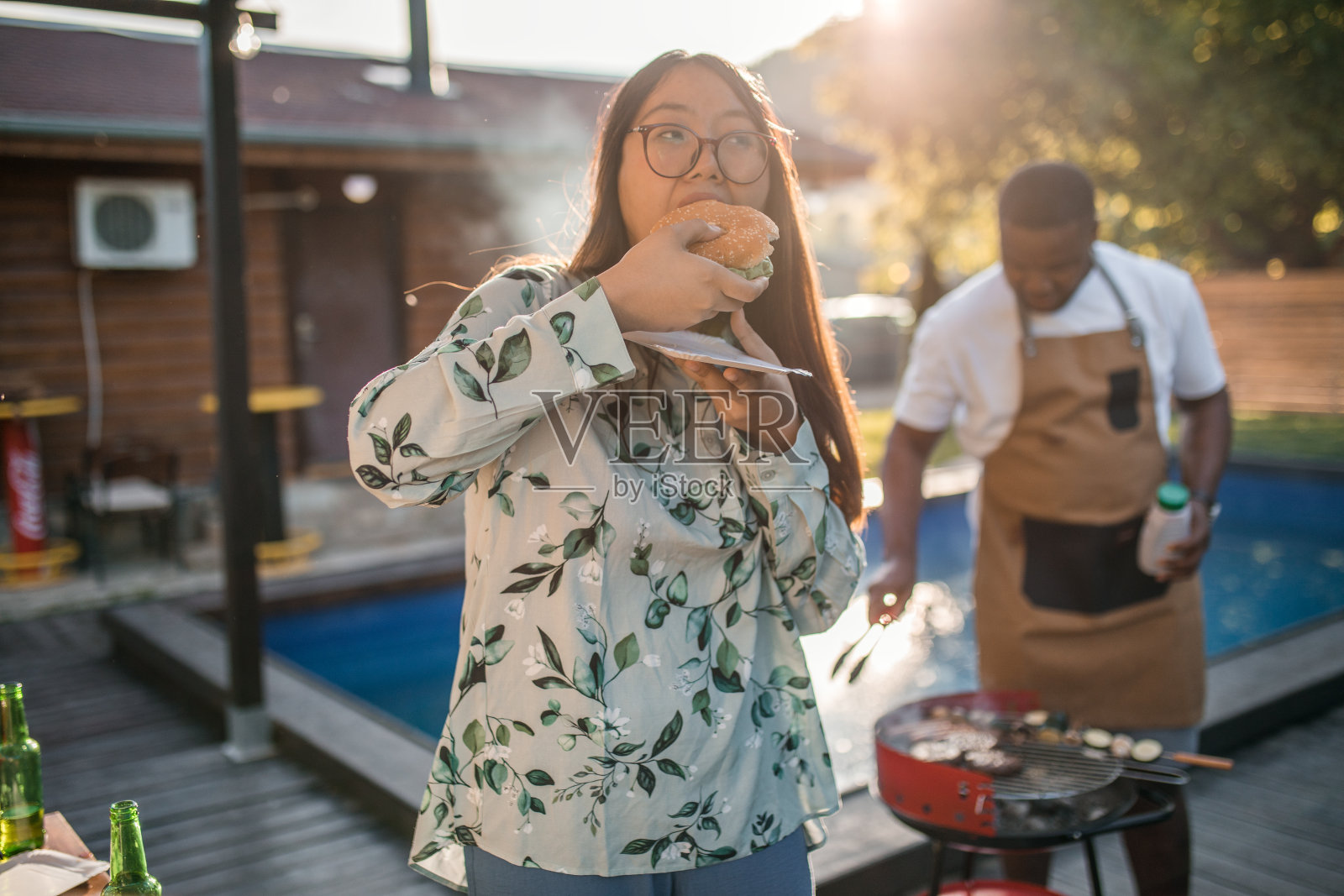 无忧无虑的亚洲女人喜欢在和朋友出去玩的时候在游泳池边吃汉堡照片摄影图片