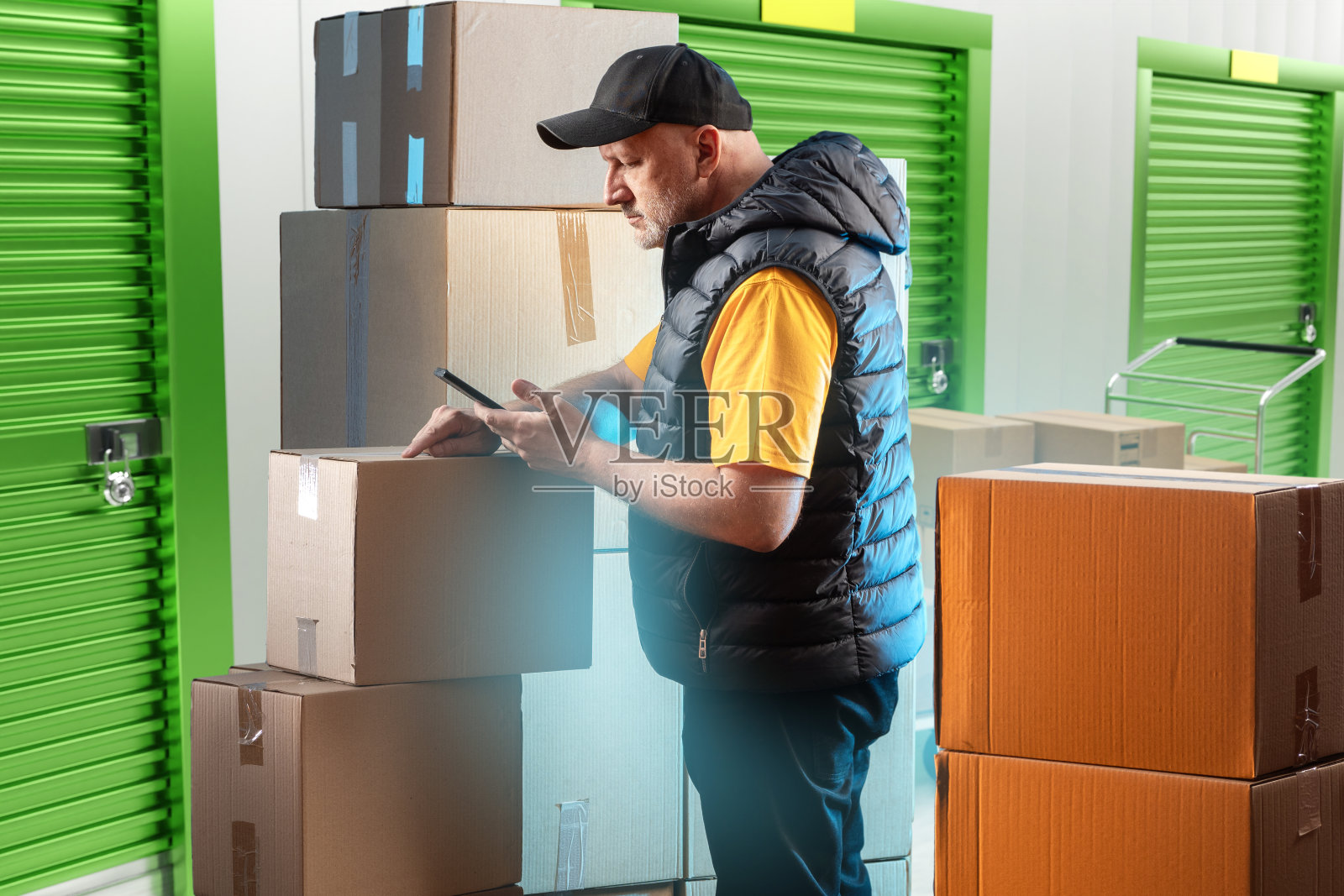 储藏室的主人。在仓库里拿箱子的人。存储单元的所有者进行盘点。人站在仓库走廊上。一名男子站在封闭的储藏室附近。照片摄影图片