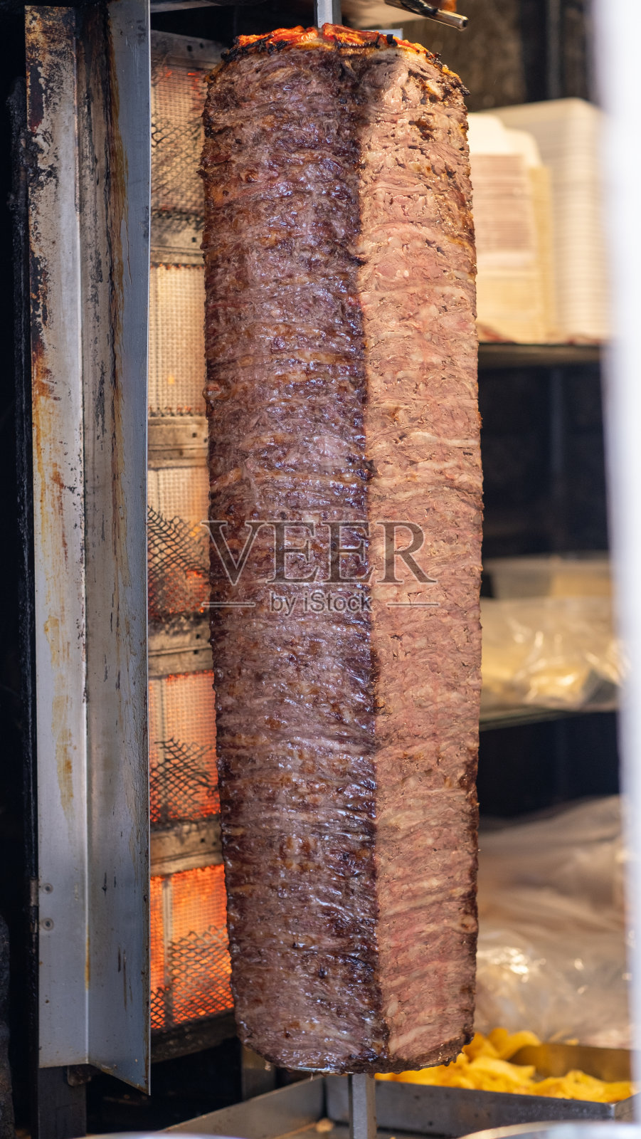 厨师熟练地从旋转的烤肉串上切下沙瓦玛肉。刚煮熟的照片摄影图片