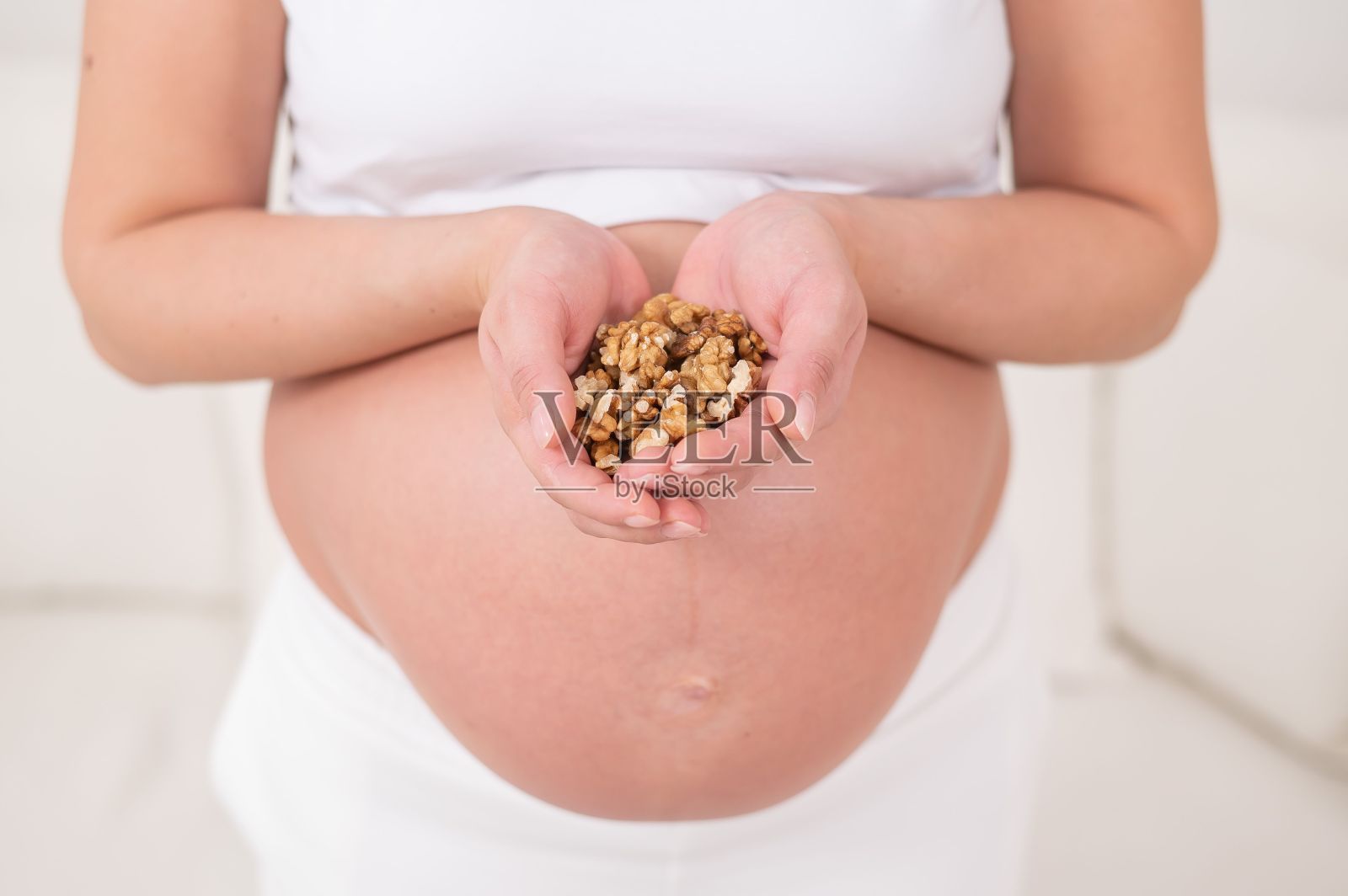 孕妇拿着一把核桃。照片摄影图片