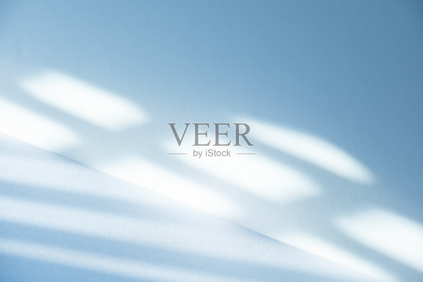 工作室风格的背景墙装饰呈现采用白色和蓝色调。阴影从附近的窗户投射出来，创造了一个装饰性的概念照片摄影图片